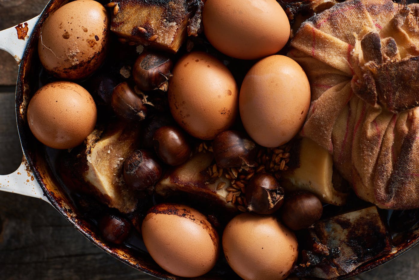 Coolant with baked eggs, chestnuts, beef bones and cheesecloth with rice in white cast iron dish.