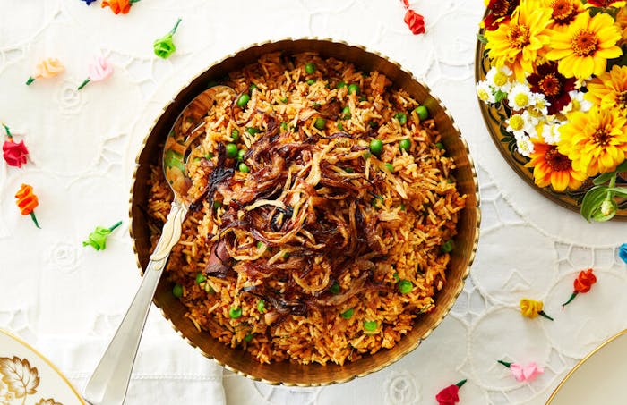 Harissa topped with crunchy burnt onions, fresh flowers, colorful paper roses.