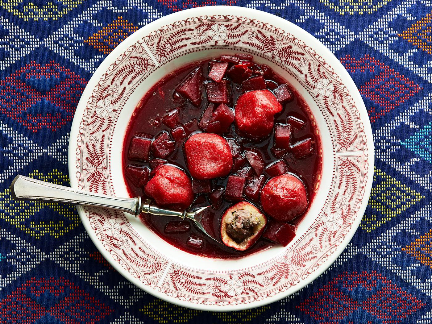 Beet kubbeh soup in red and white plate.