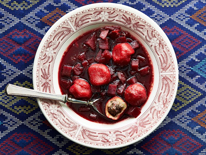 Beet kubbeh soup in red and white plate.