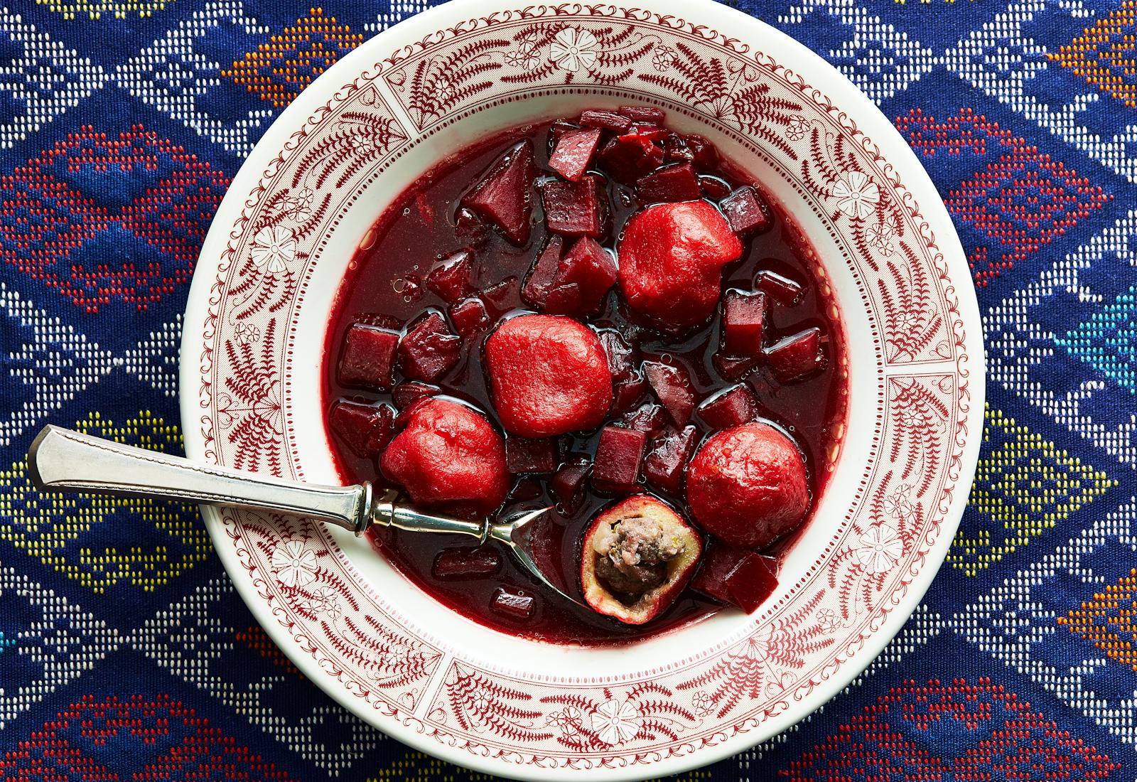 Beet kubbeh soup in red and white plate.