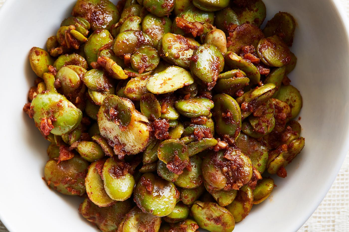 Sauteed fava beans coated in spices in white bowl.