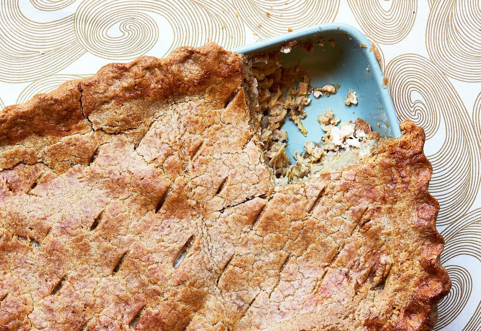 Pastel de merengena in blue casserole dish atop tan and white tablecloth.