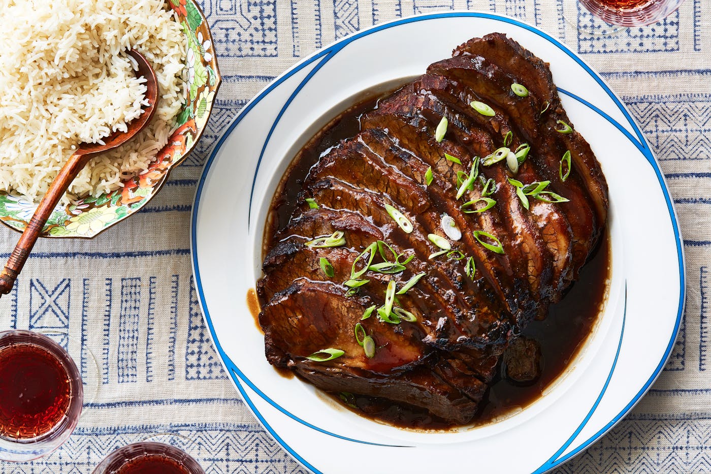 Sliced Taiwanese brisket on blue and white plate alongside bowl of rice.