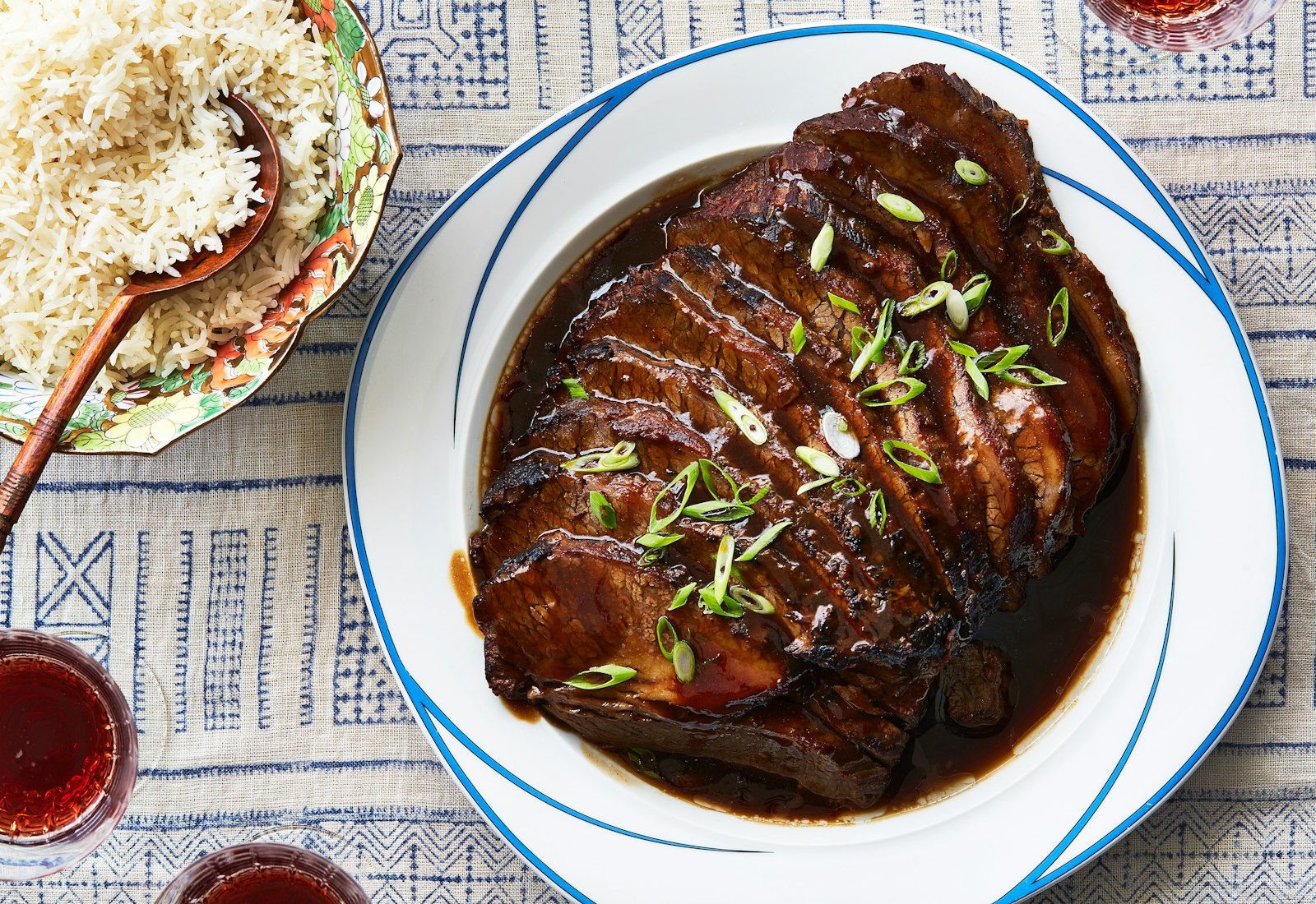 Sliced Taiwanese brisket on blue and white plate alongside bowl of rice.