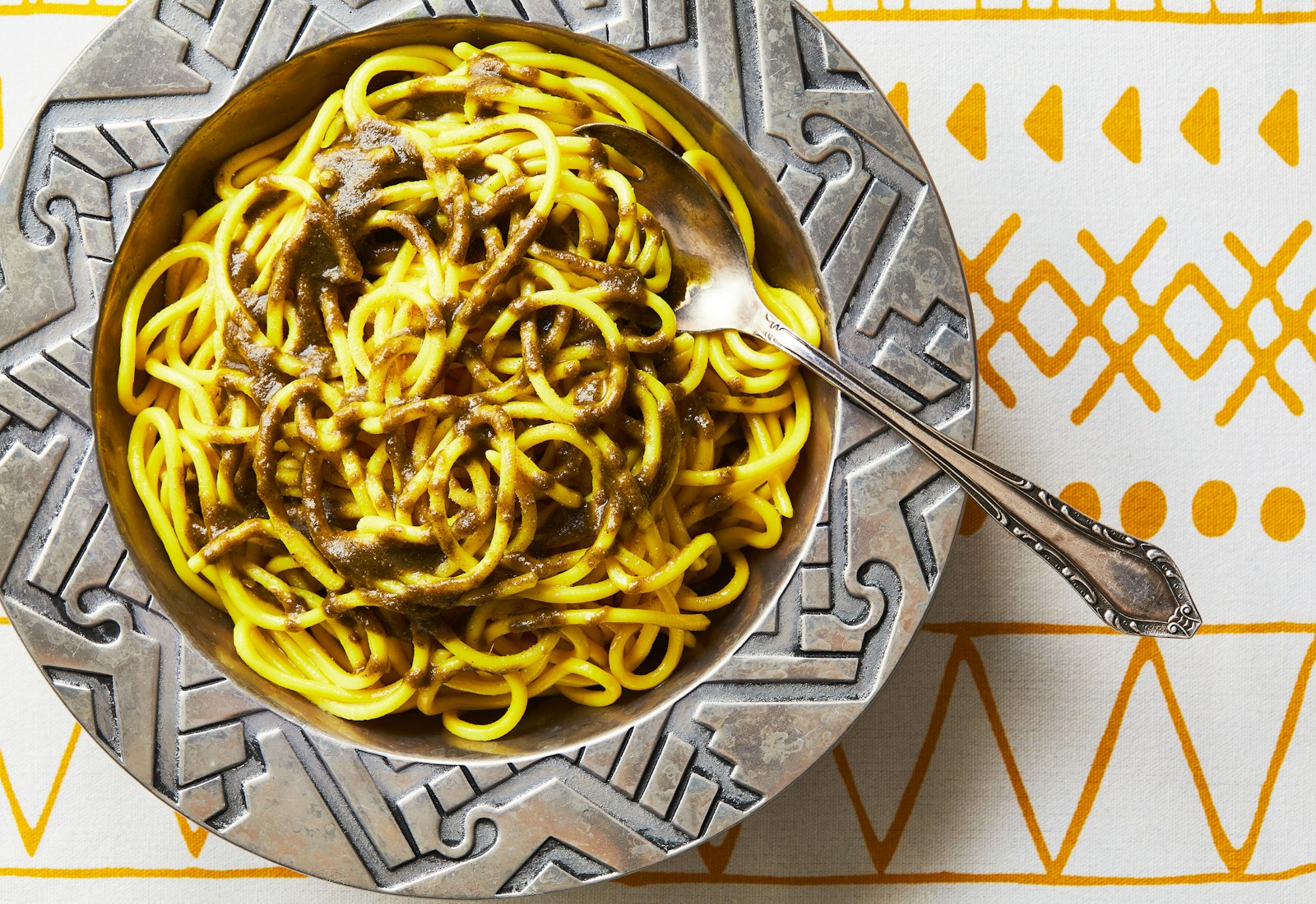 Tagareenas in silver bowl atop white and marigold tablecloth.