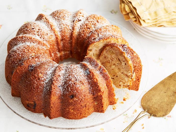 Apple cake with powdered sugar, gold pie server and yellow napkins. 