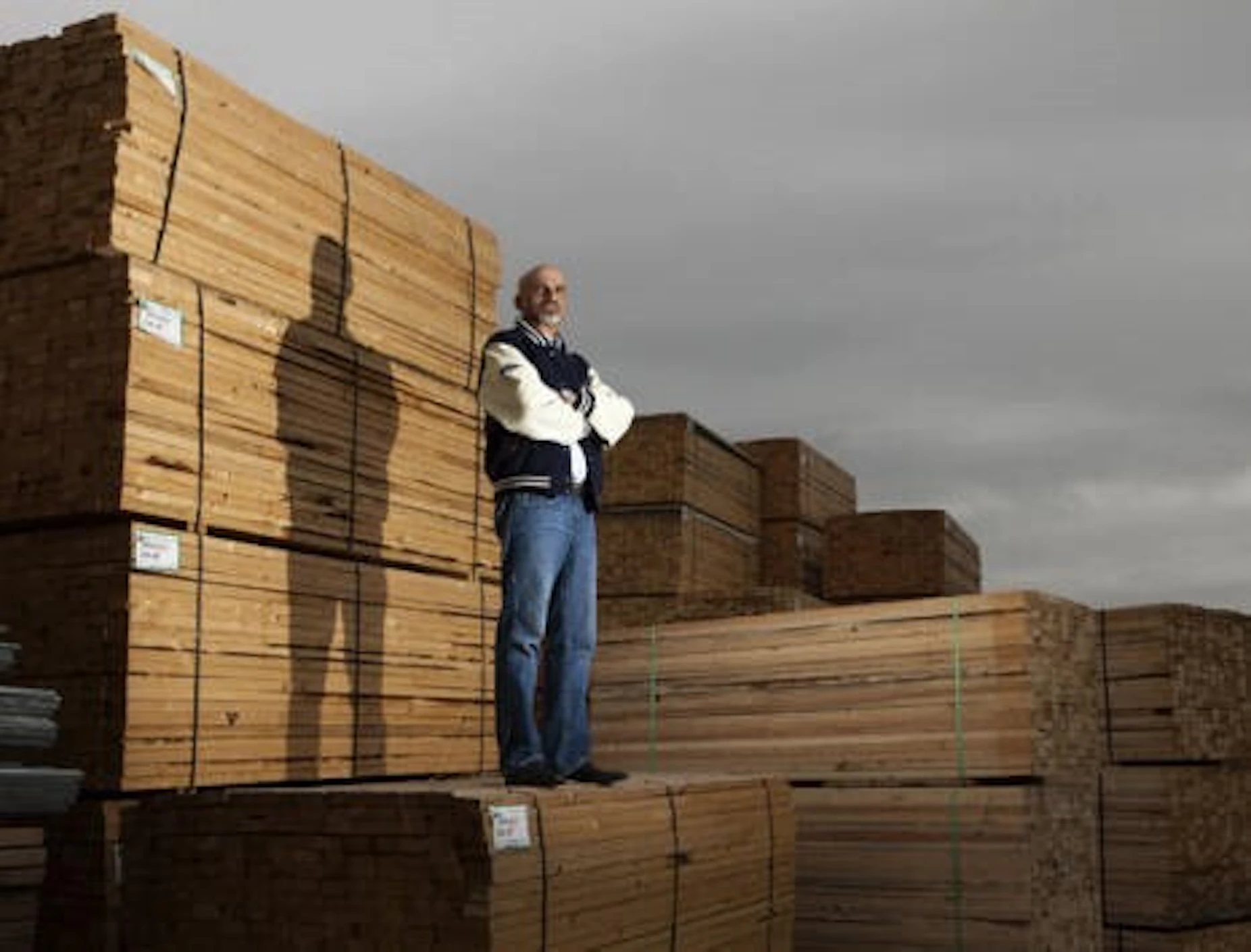 Parm Jhajj standing next to a pile of lumber.jpg