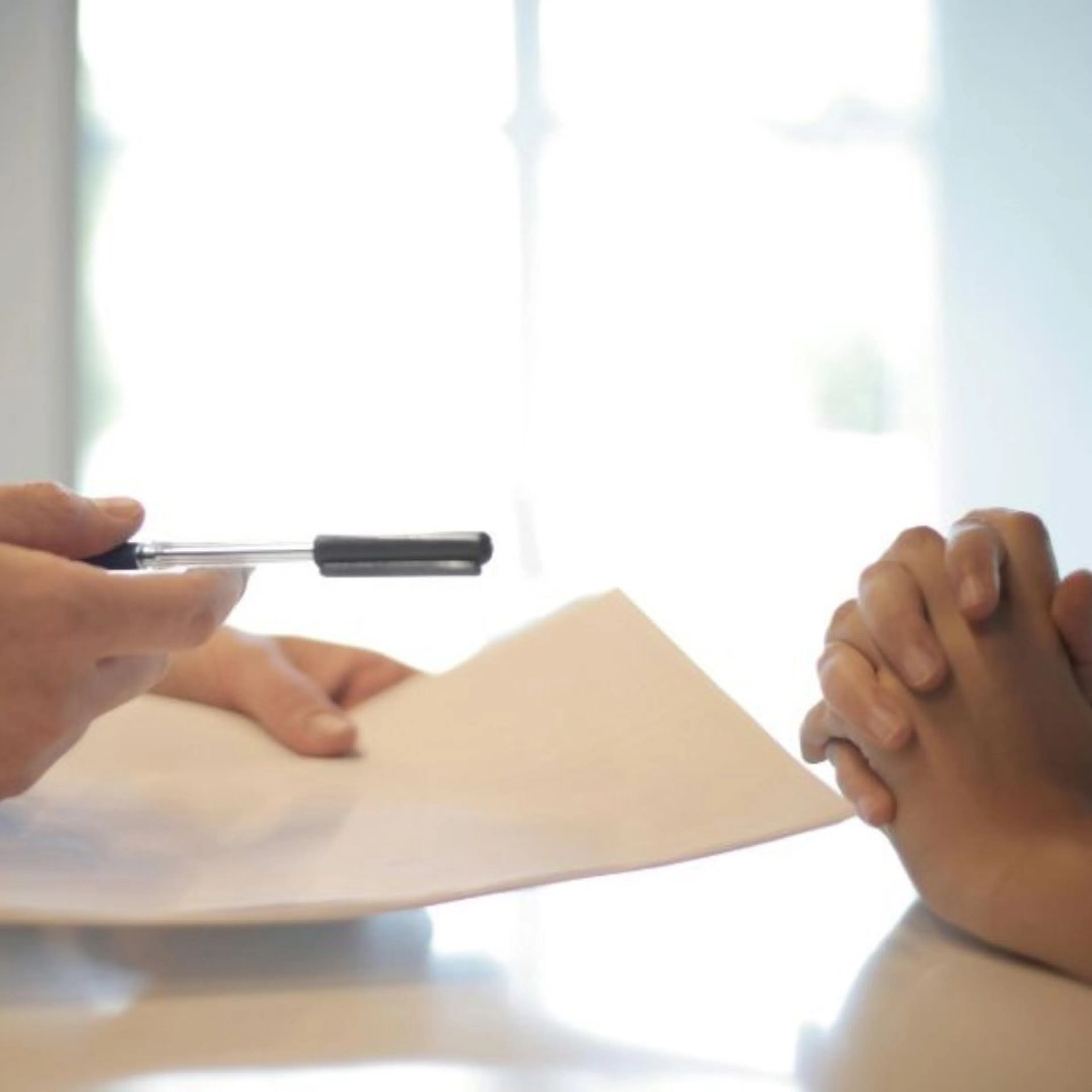 Two people exchanging a pen to sign a contract