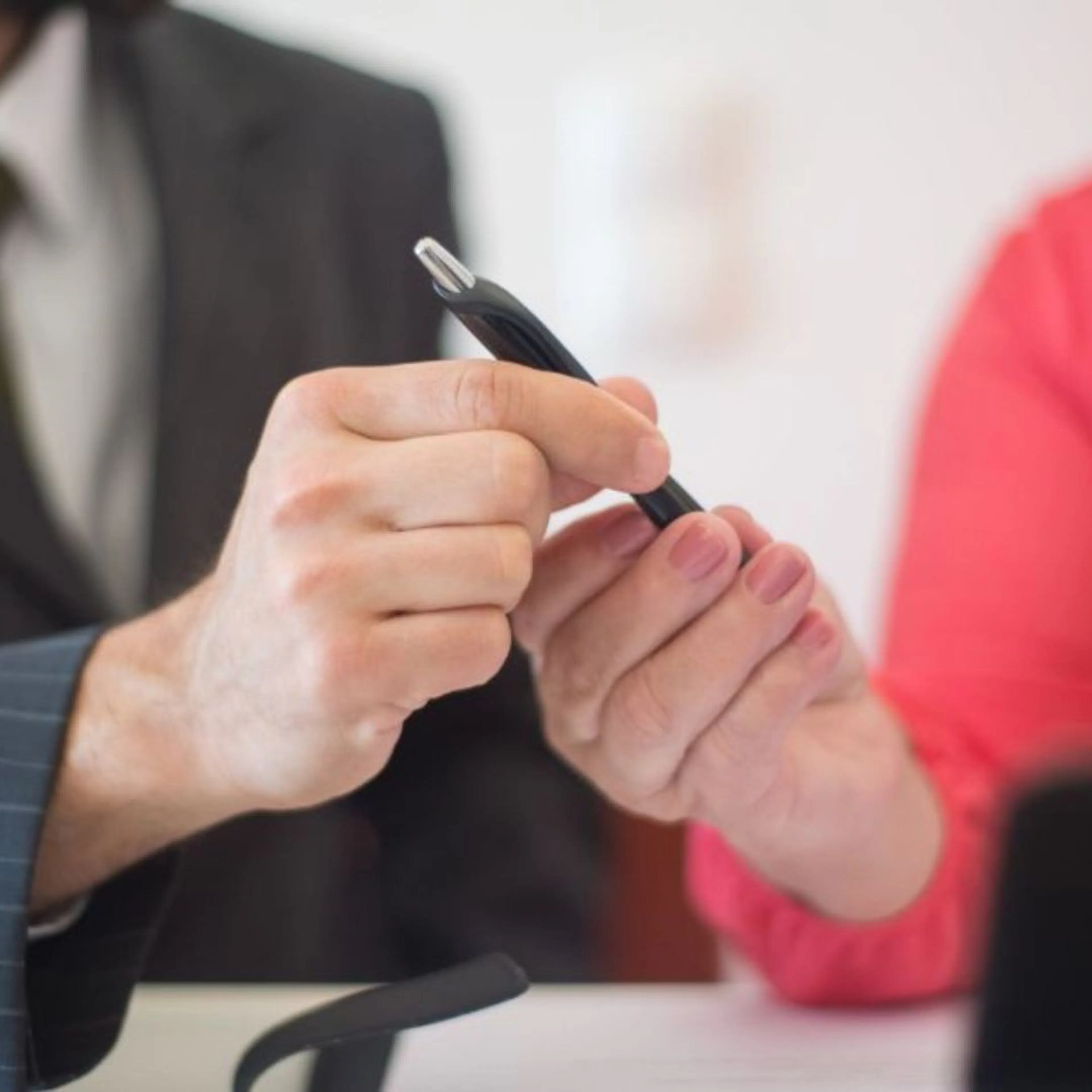 Two people exchanging a pen to sign a contract