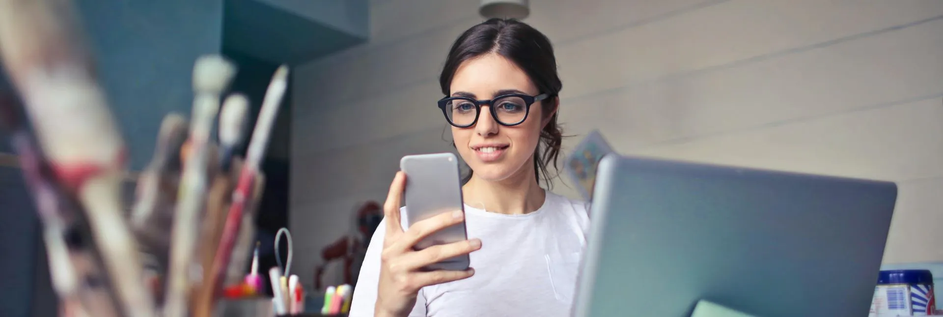 Close-up of a person typing on a laptop and checking a mobile phone