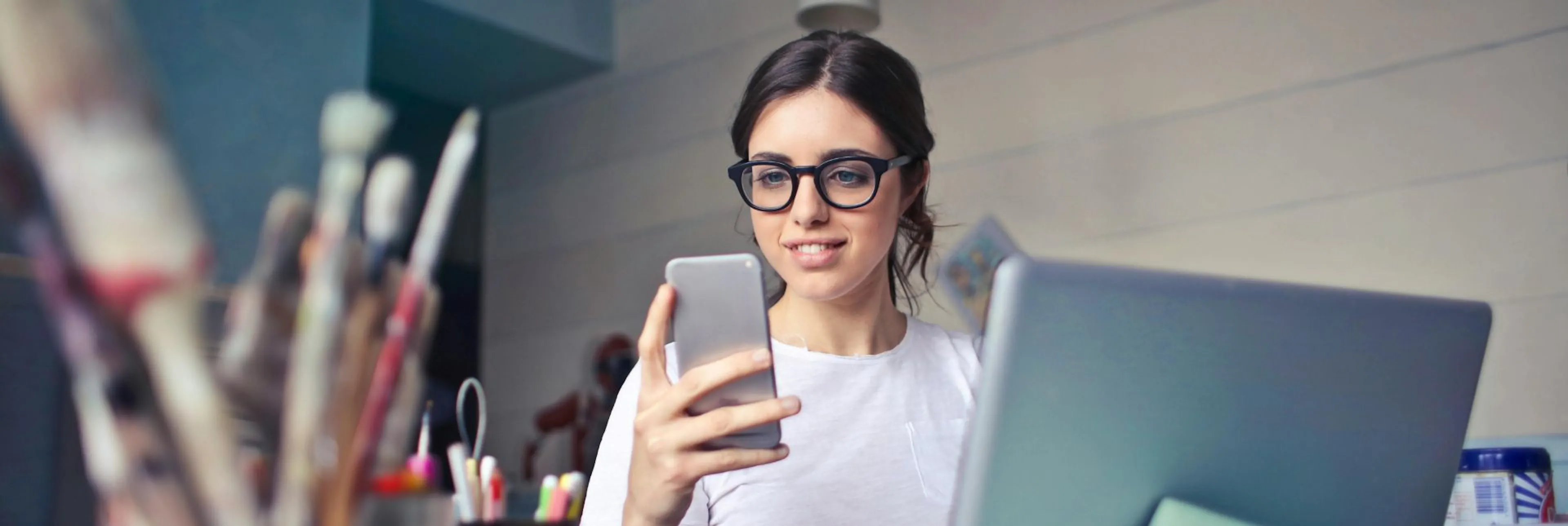 Close-up of a person typing on a laptop and checking a mobile phone