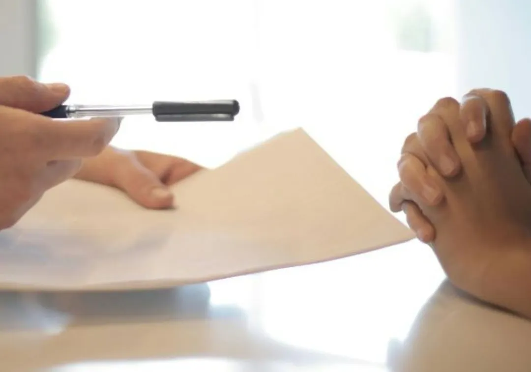 Two people exchanging contract papers