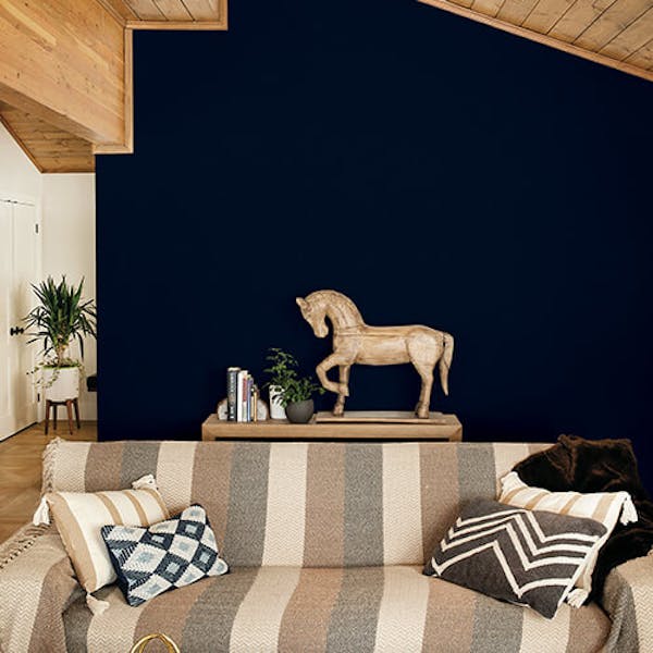 dark blue wall with a striped sofa