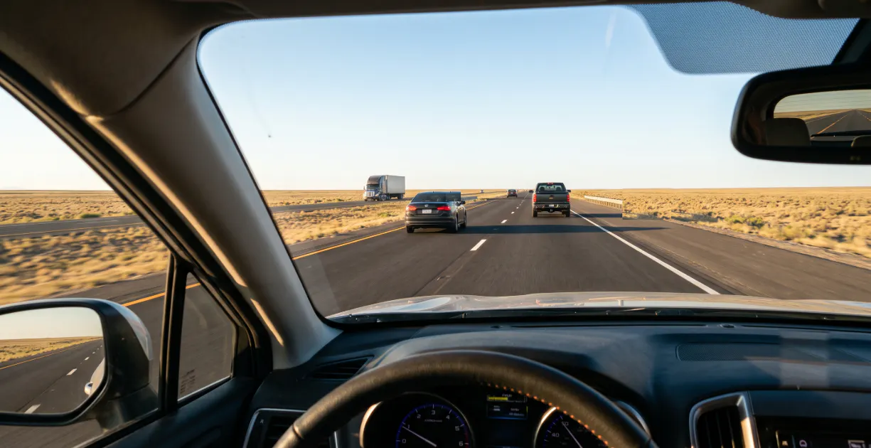 image of someone looking out of their car window while driving down a highway