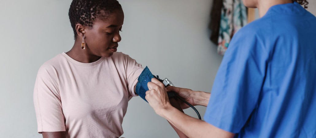 Image of a woman in a doctor's office having her blood pressure taken by a medical professional