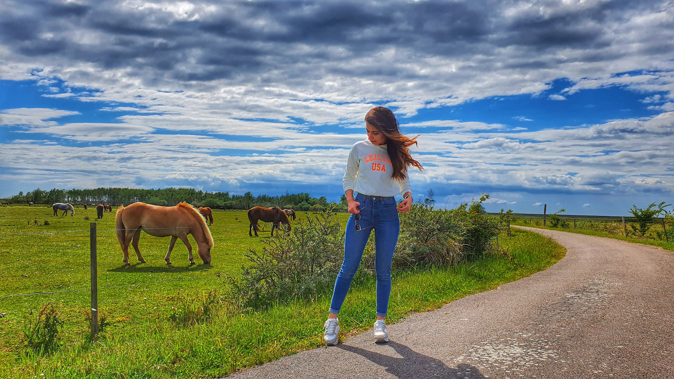 LifeX member Sonia posing with horses in the background in one of Copenhagen's nature spaces