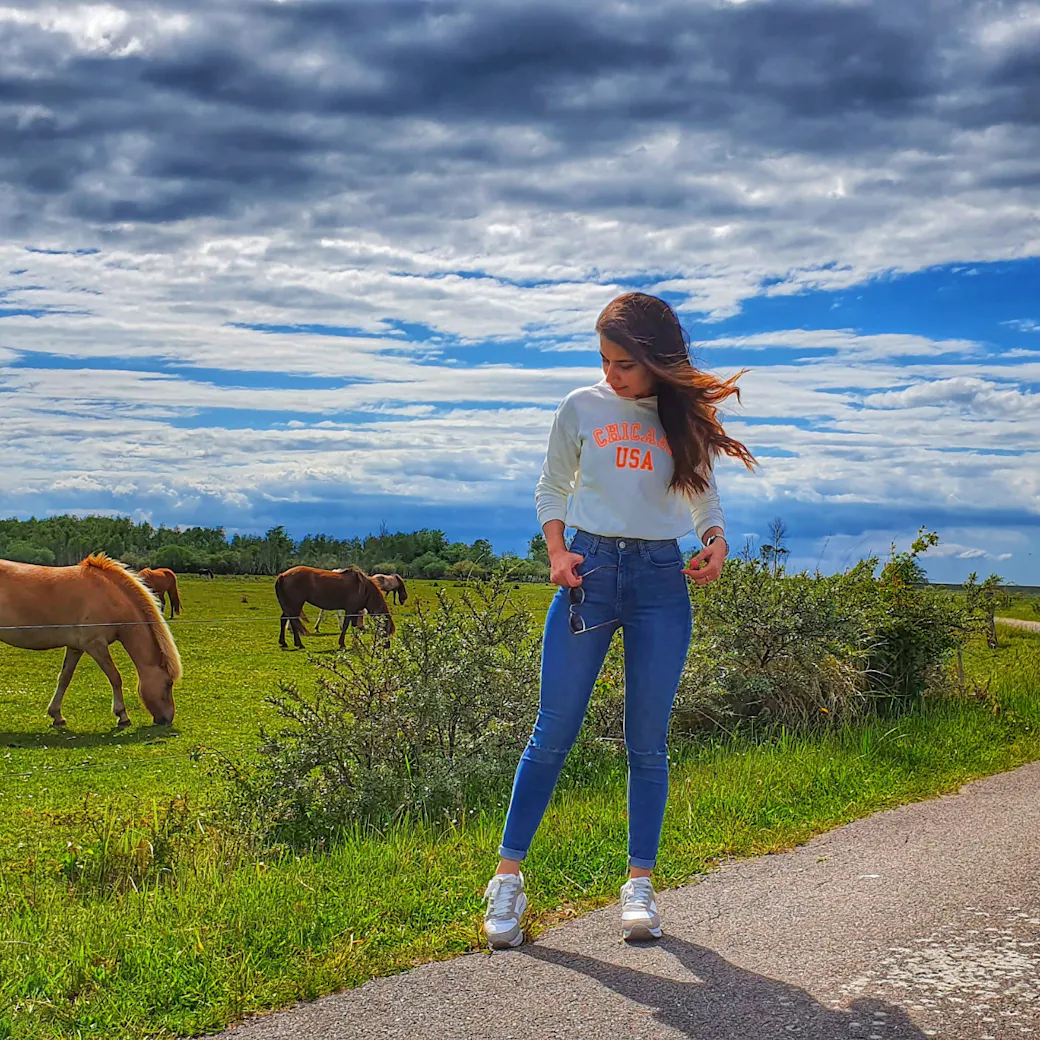 LifeX member Sonia posing with horses in the background in one of Copenhagen's nature spaces
