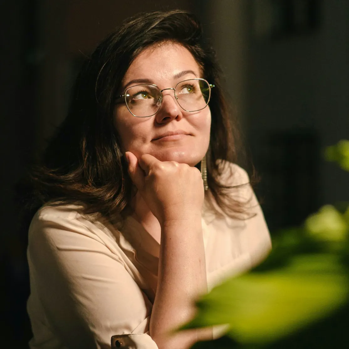 A woman in midlife with her hand on her chin, looking up into the light. She's thinking about the connection between menopause and high cholesterol.