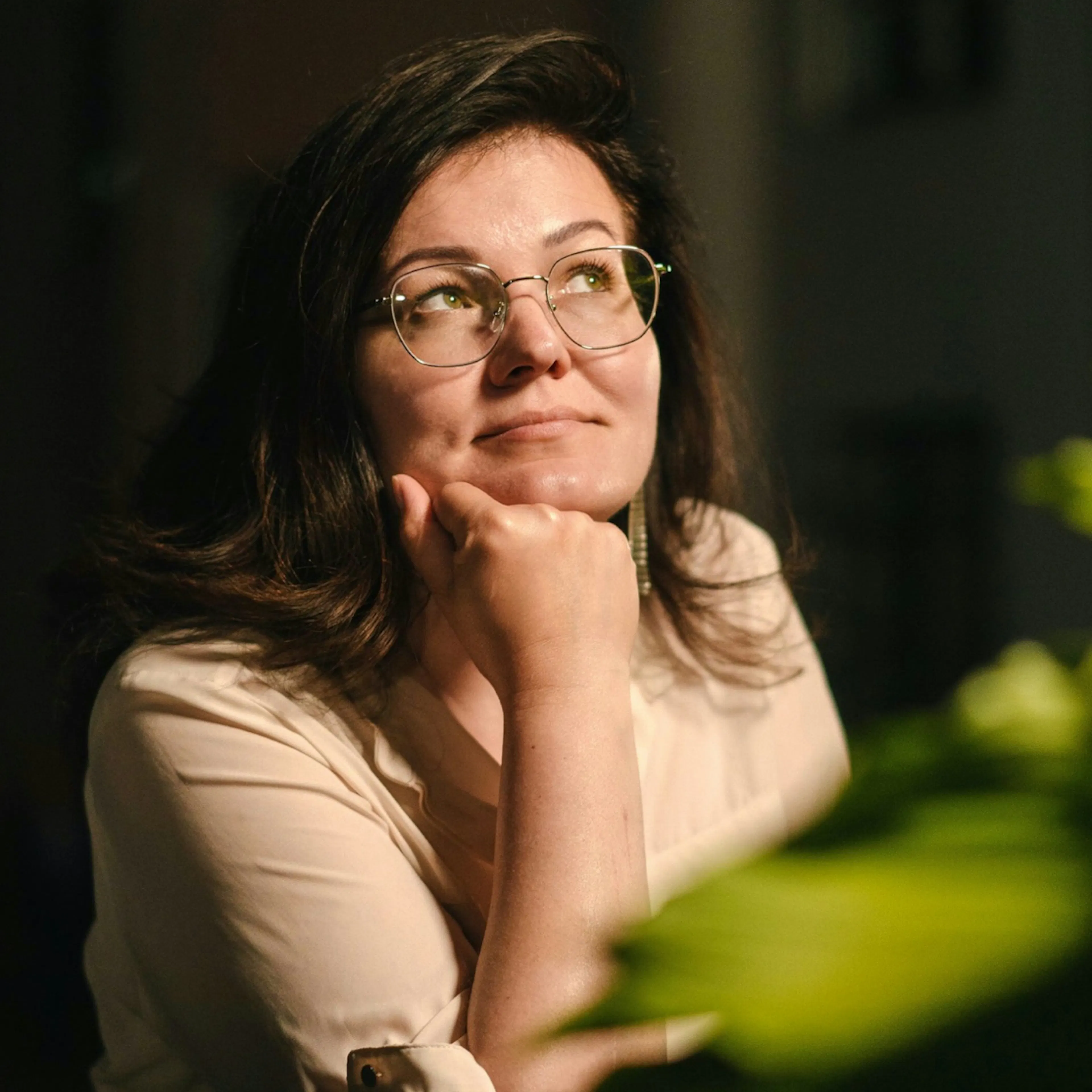 A woman in midlife with her hand on her chin, looking up into the light. She's thinking about the connection between menopause and high cholesterol.