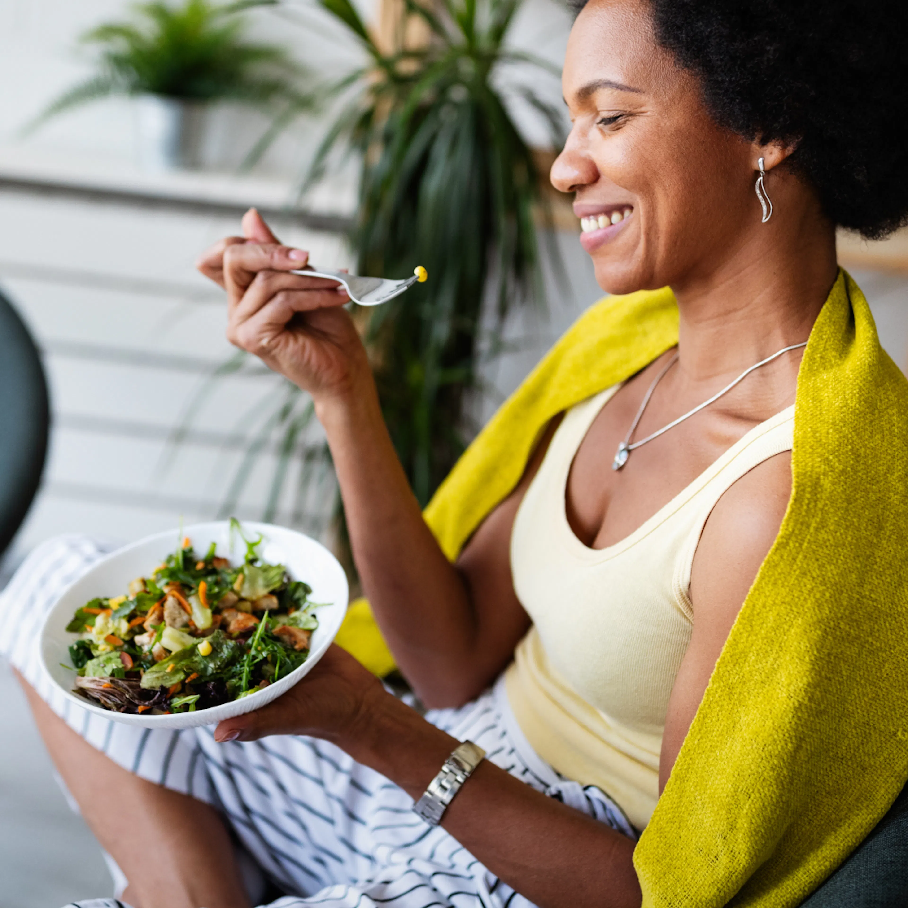 A woman eating a salad full of veggies.