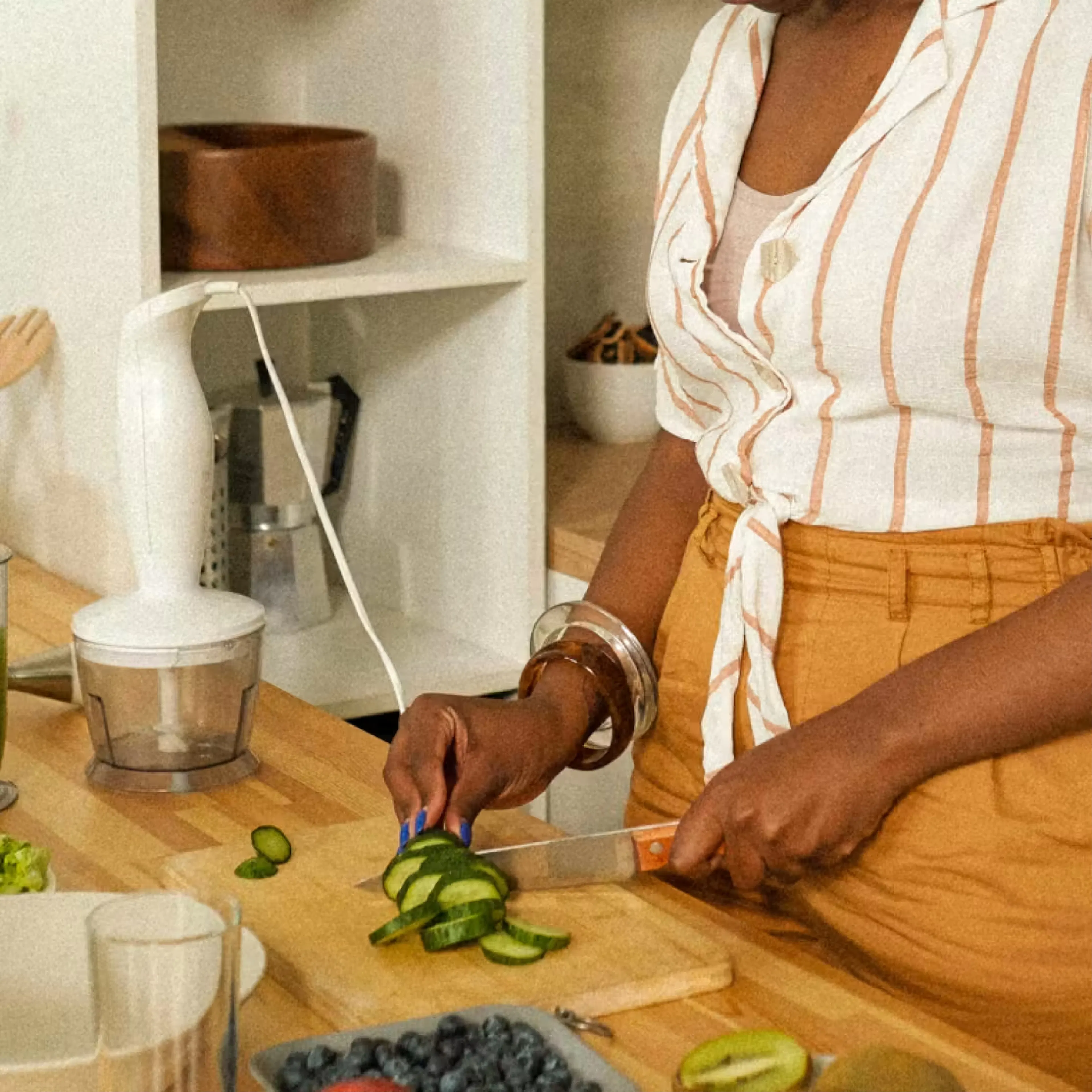Person slicing cucumbers on wooden board