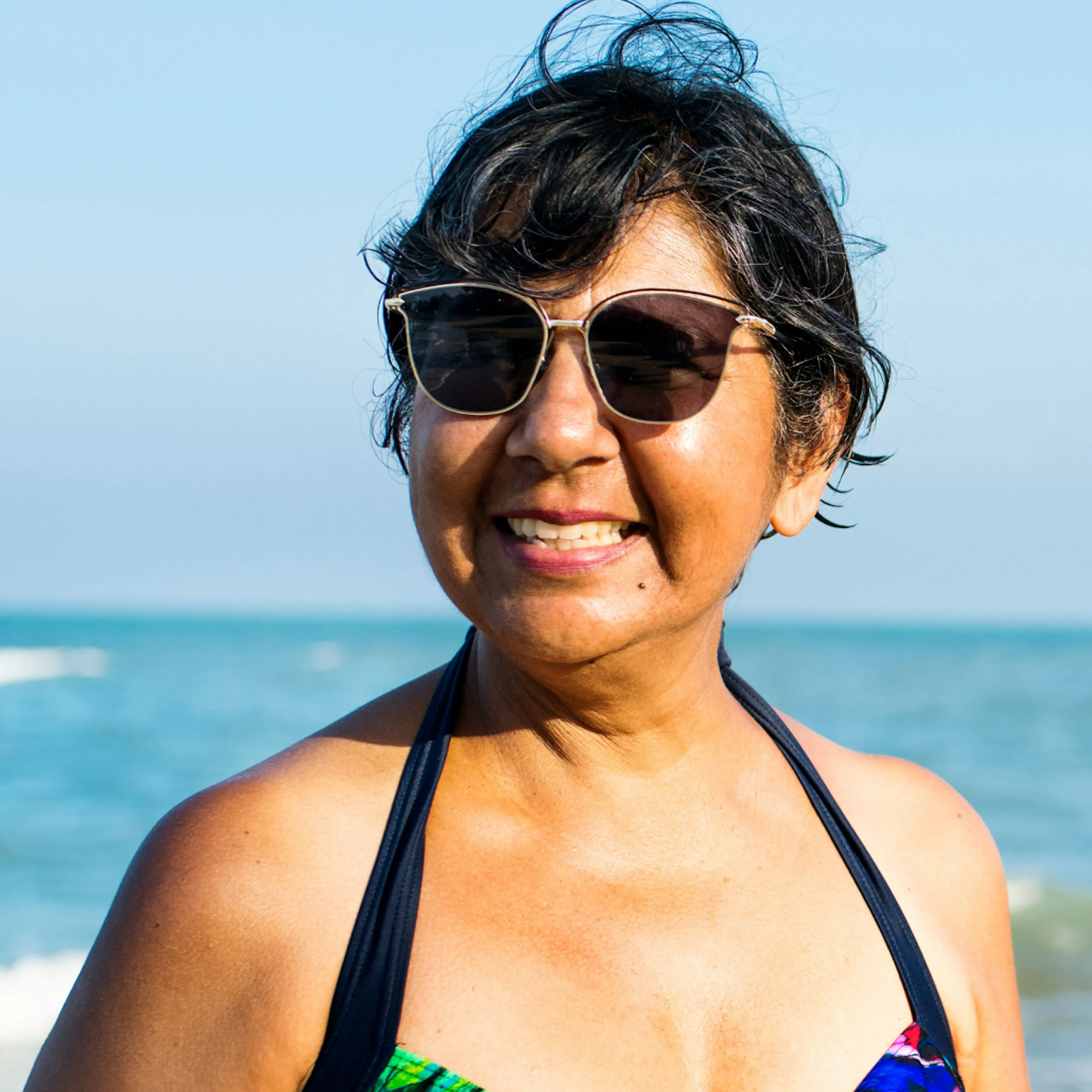 A menopausal woman in Florida, smiling on the beach.