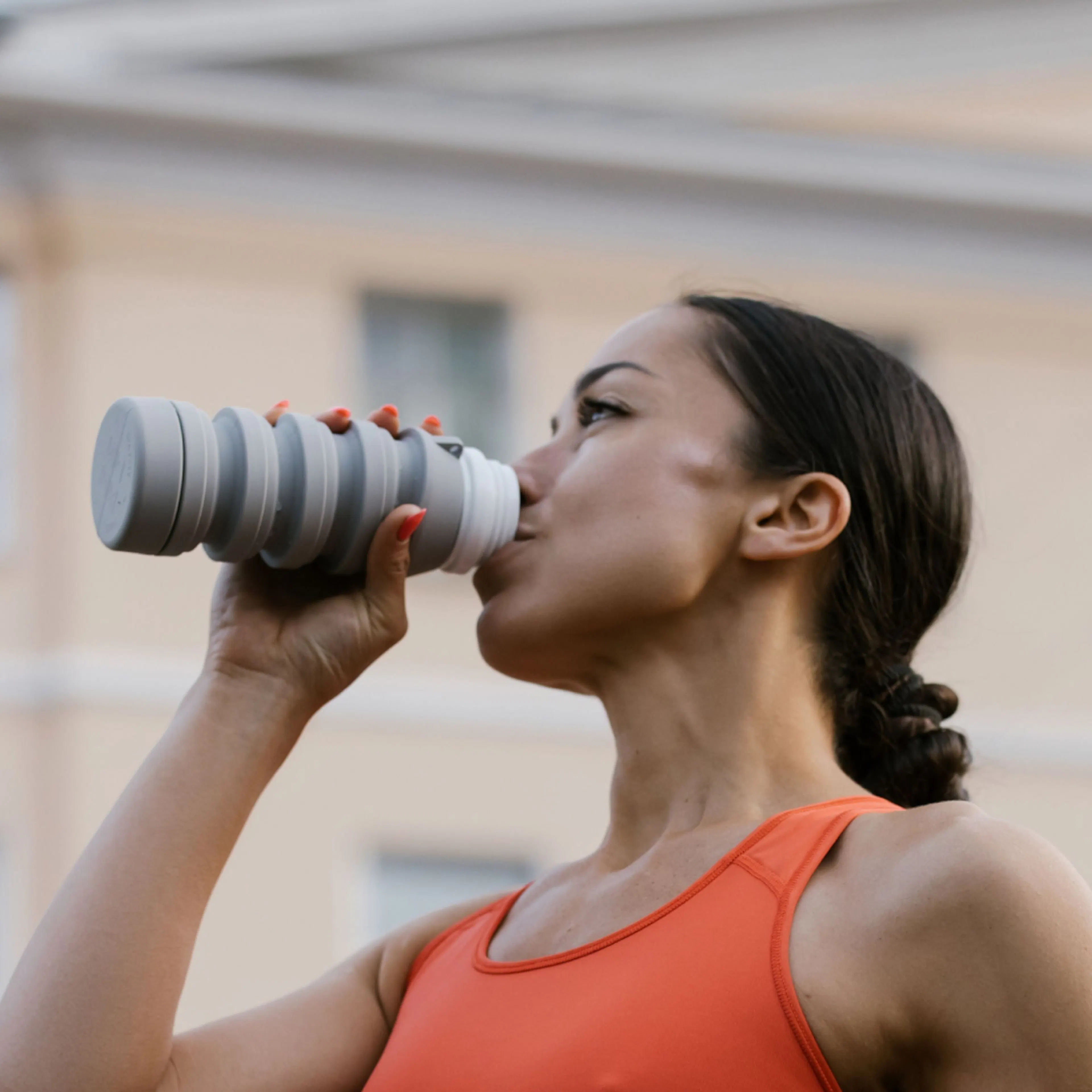 A woman in perimenopause drinking creatine in a water bottle.