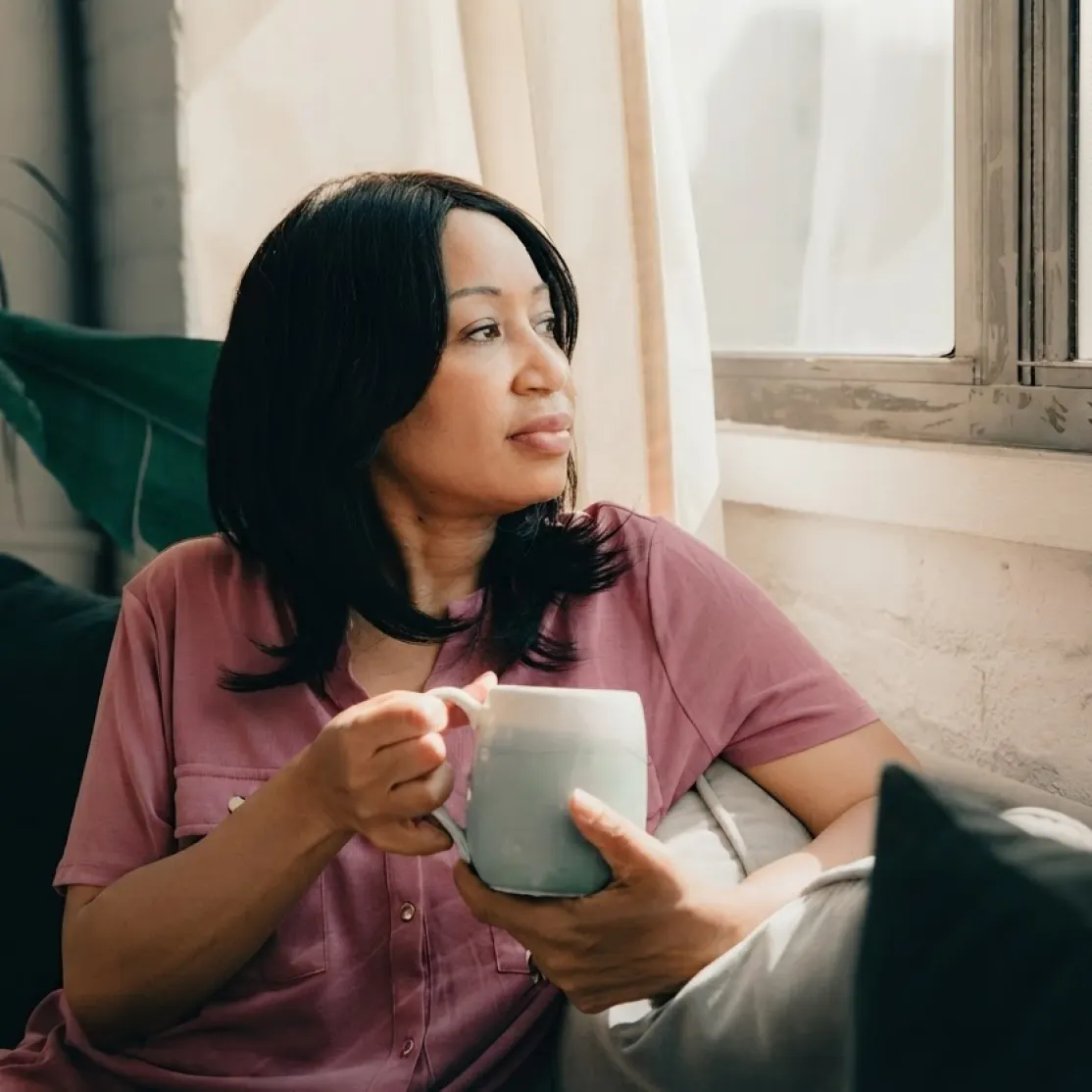 A woman sitting in her home drinking coffee from a mug. She is wondering how to get tirzepatide.