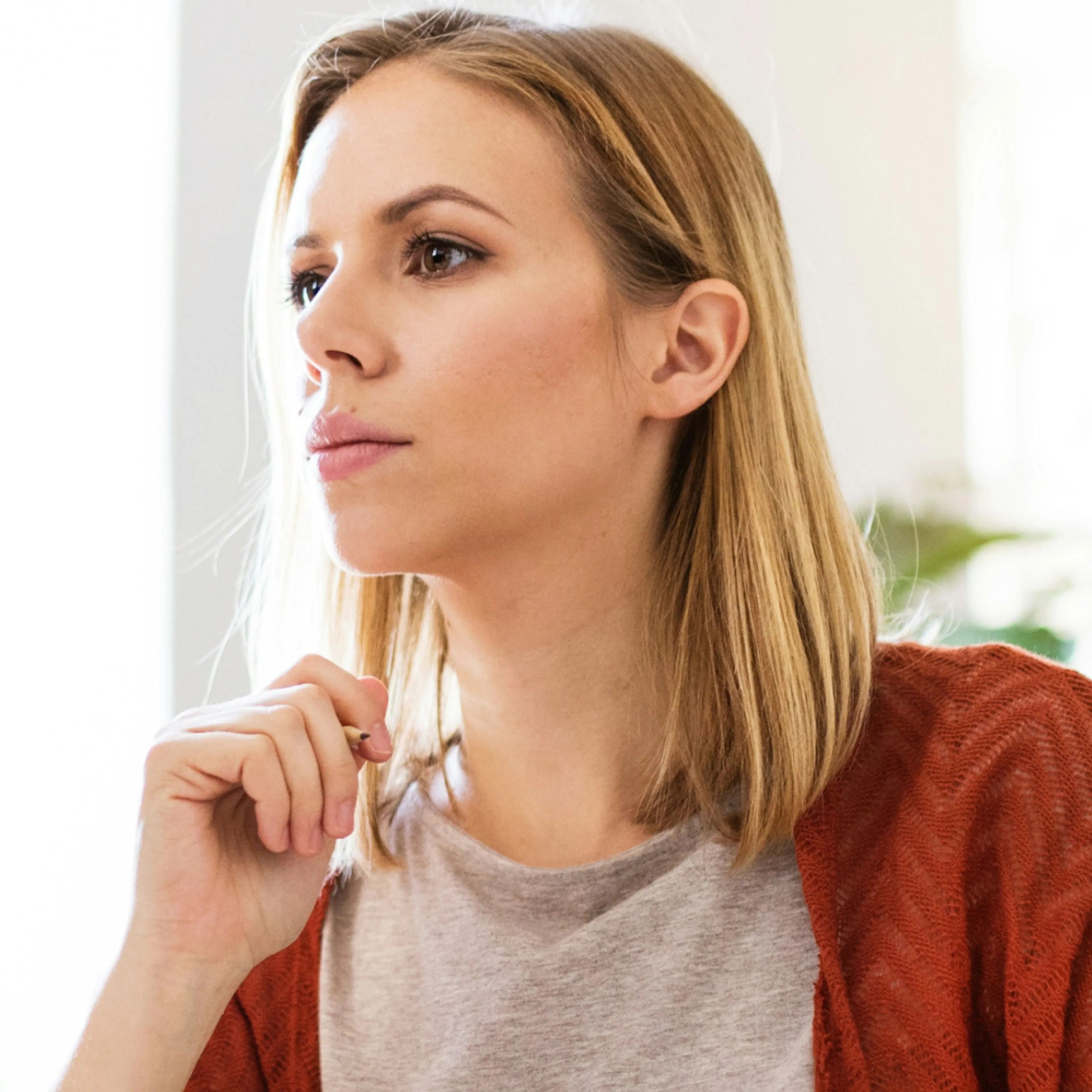 A woman in midlife thinking and looking off into the distance. She's wondering if she should take colostrum supplements.