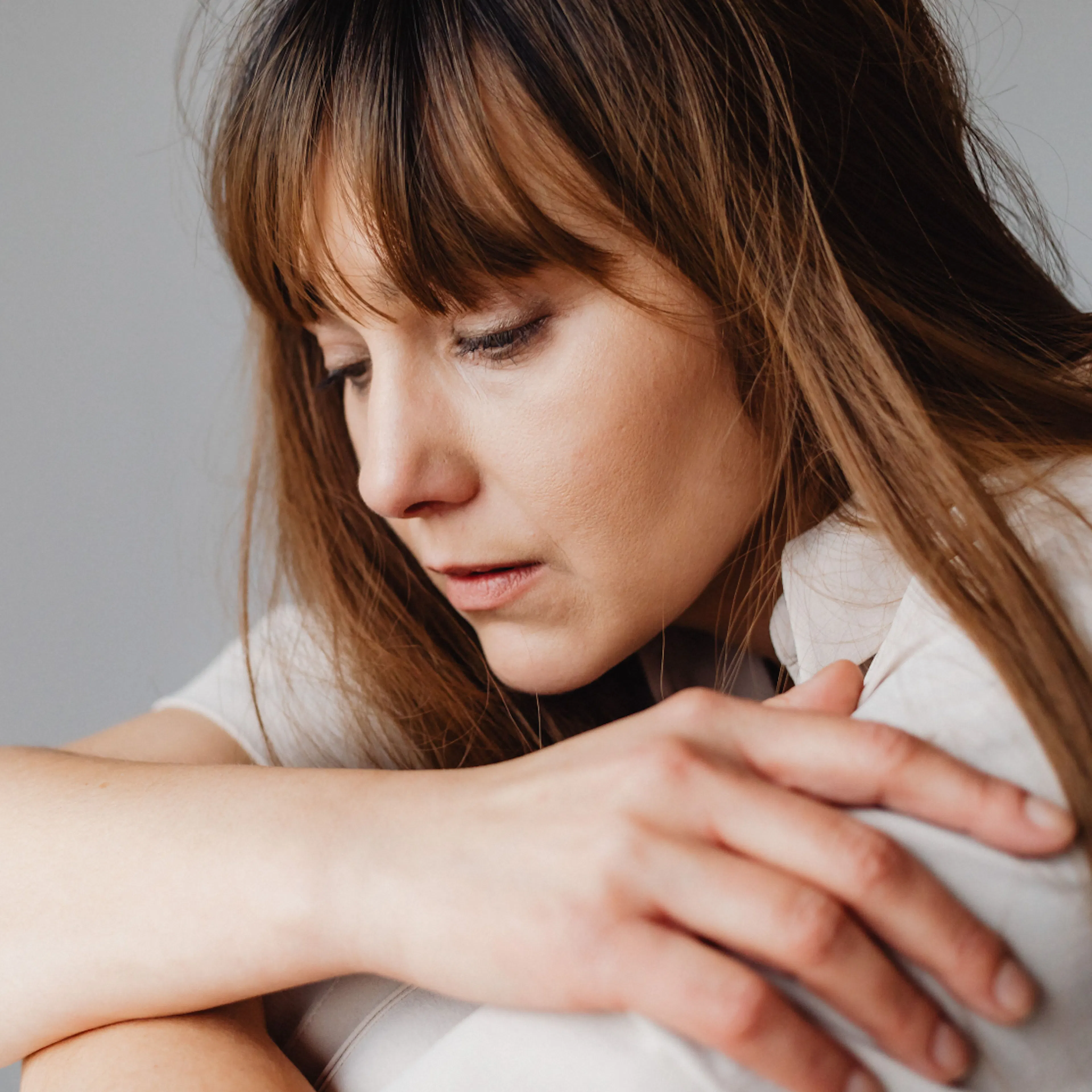 A woman looking down and sad as she potentially experiences low progesterone symptoms like mood changes.