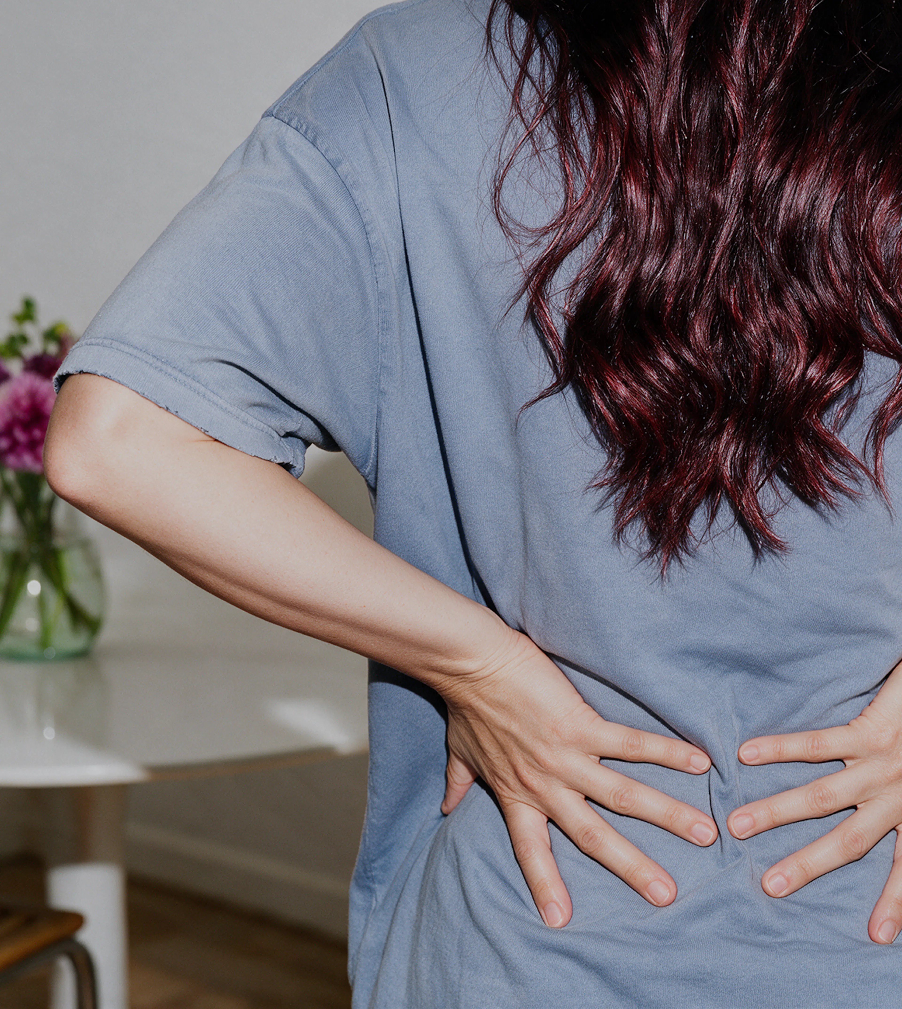 A person standing with both hands placed against their lower back