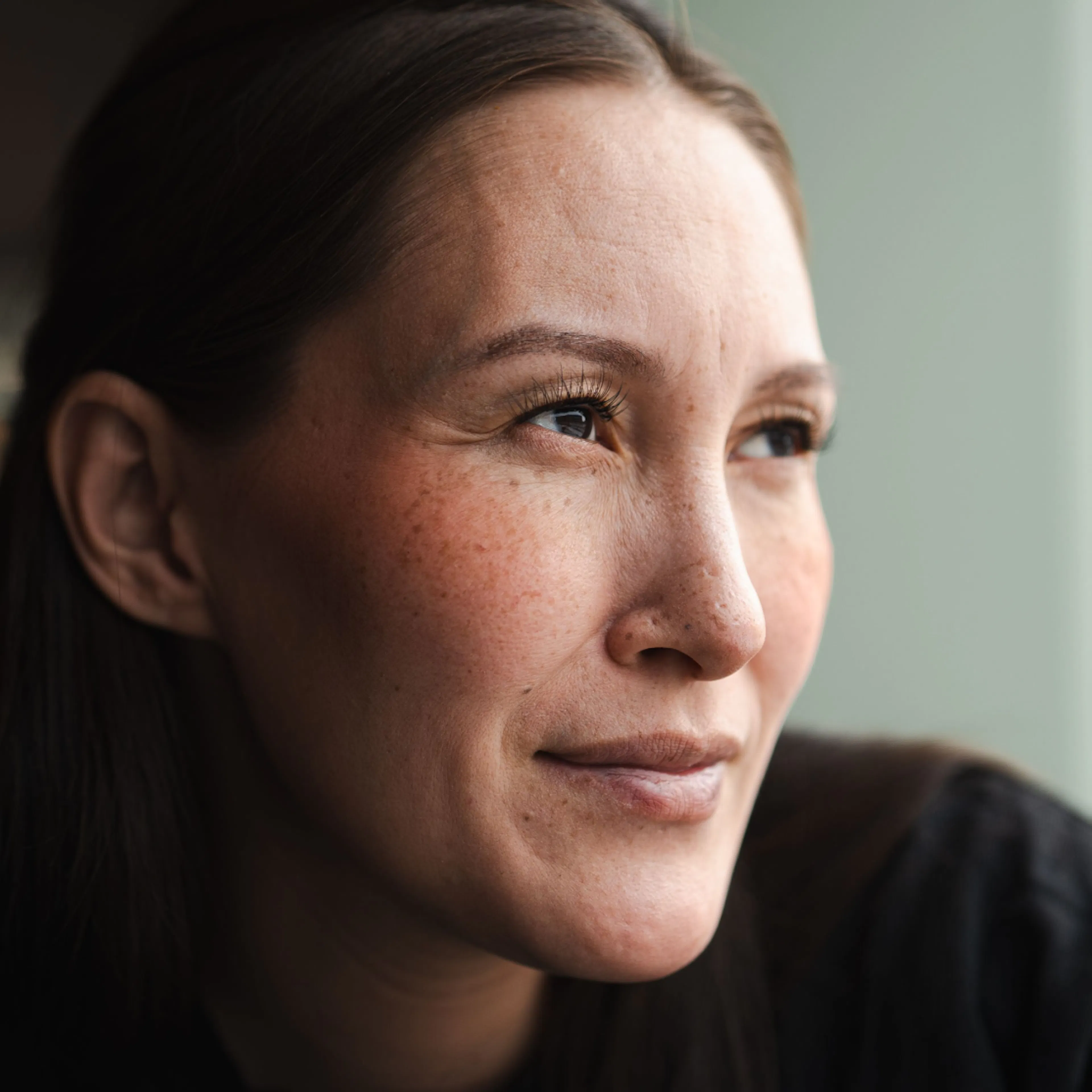 A close-up image of a woman in midlife, smiling and looking into the distance.