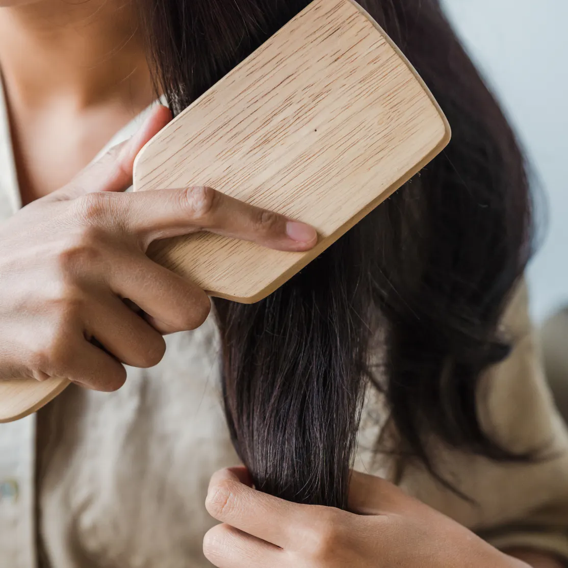 A close-up image of a woman brushing her hair with a hairbrush.