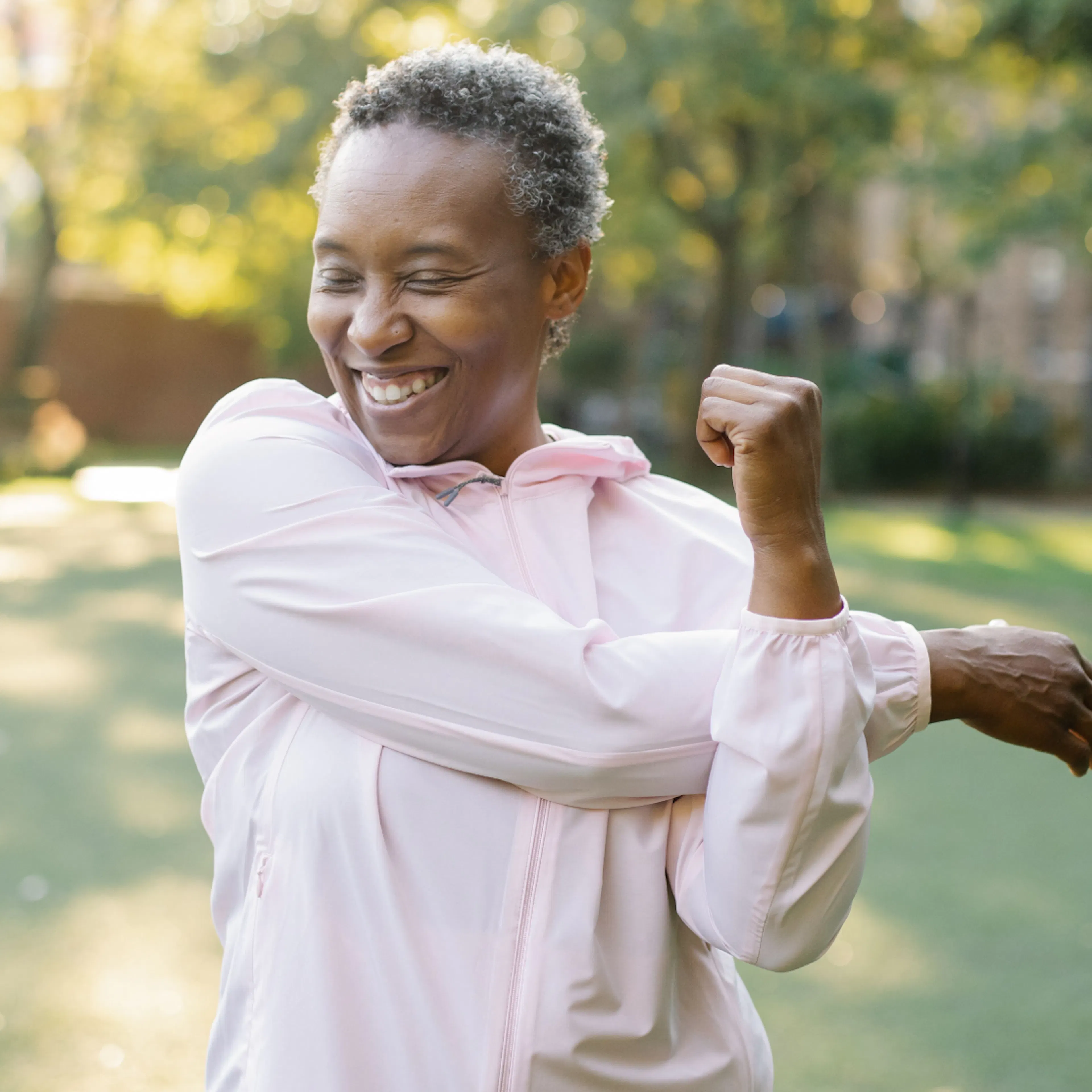A woman in midlife stretching her arms outside.