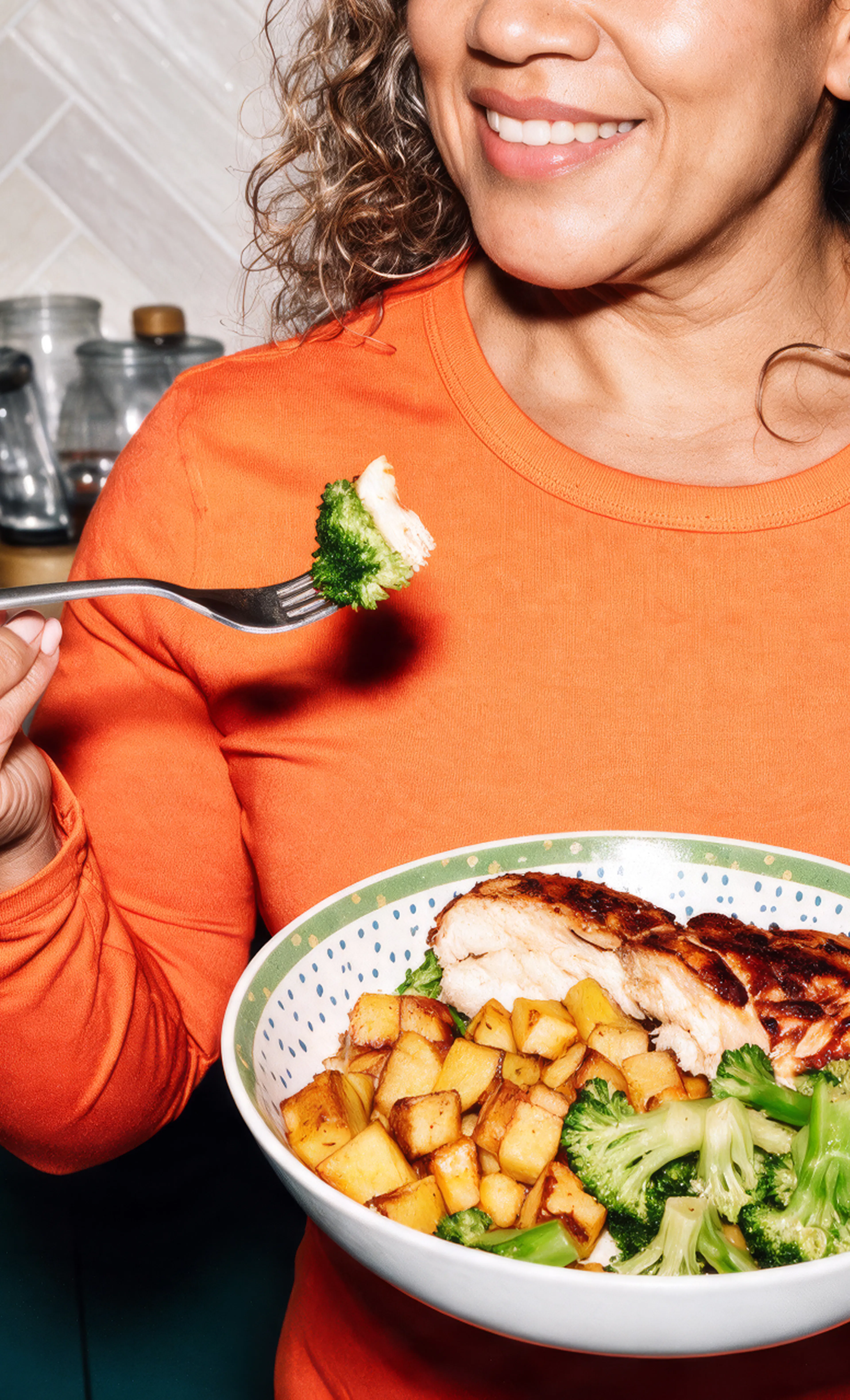 Smiling woman eating broccoli with fork