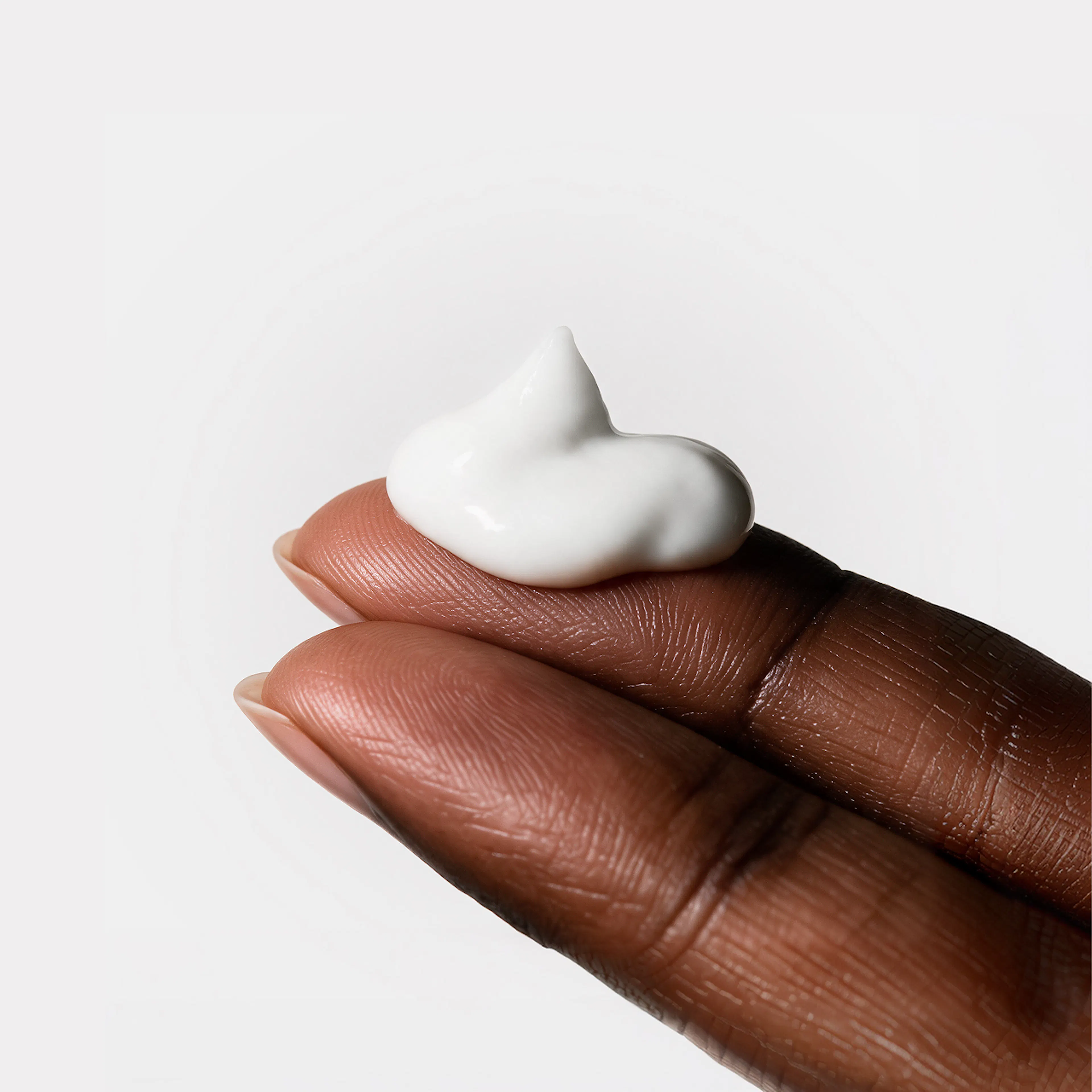 Fingertips holding a dollop of Arousal Cream.
