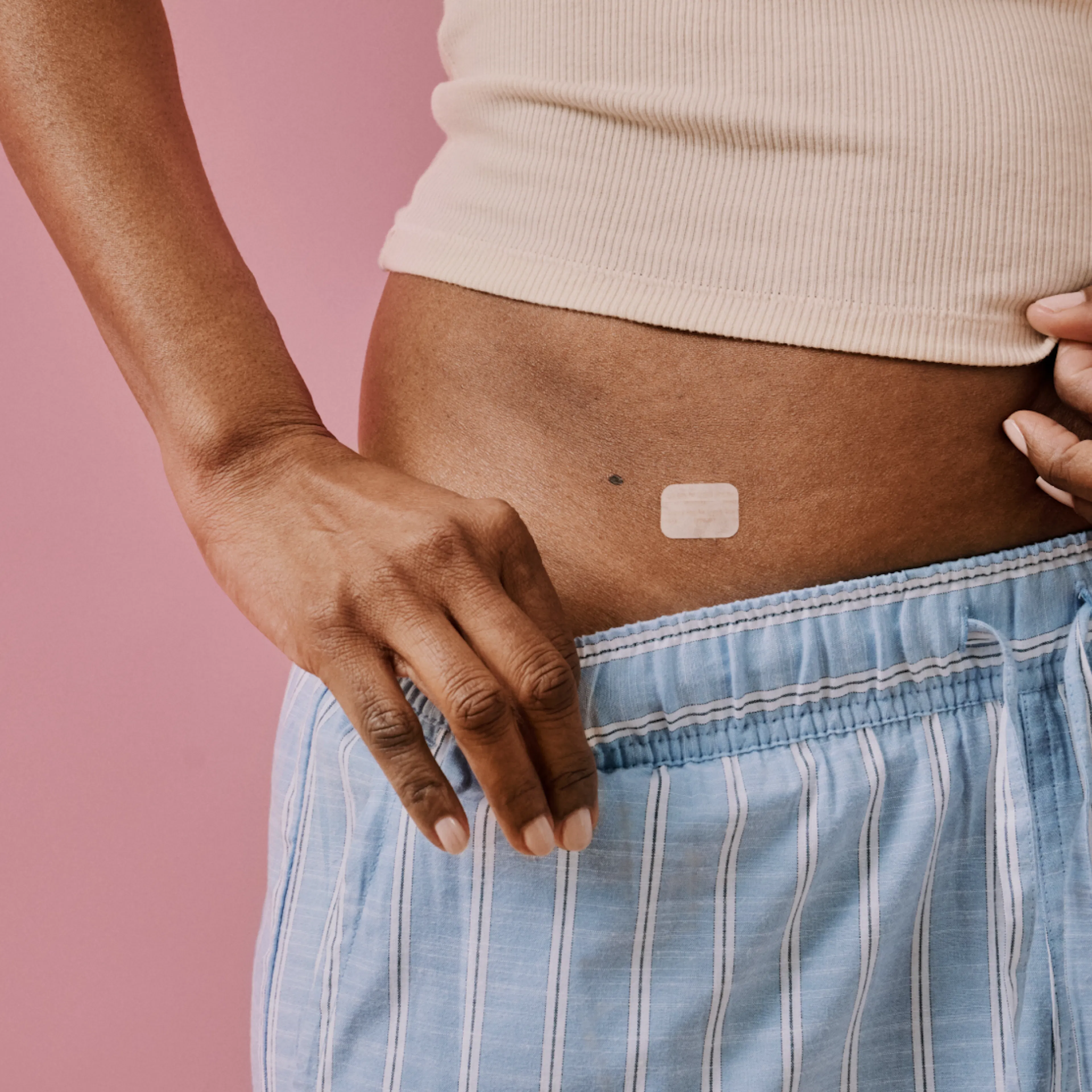 A close-up image of an estrogen patch on a woman's body.