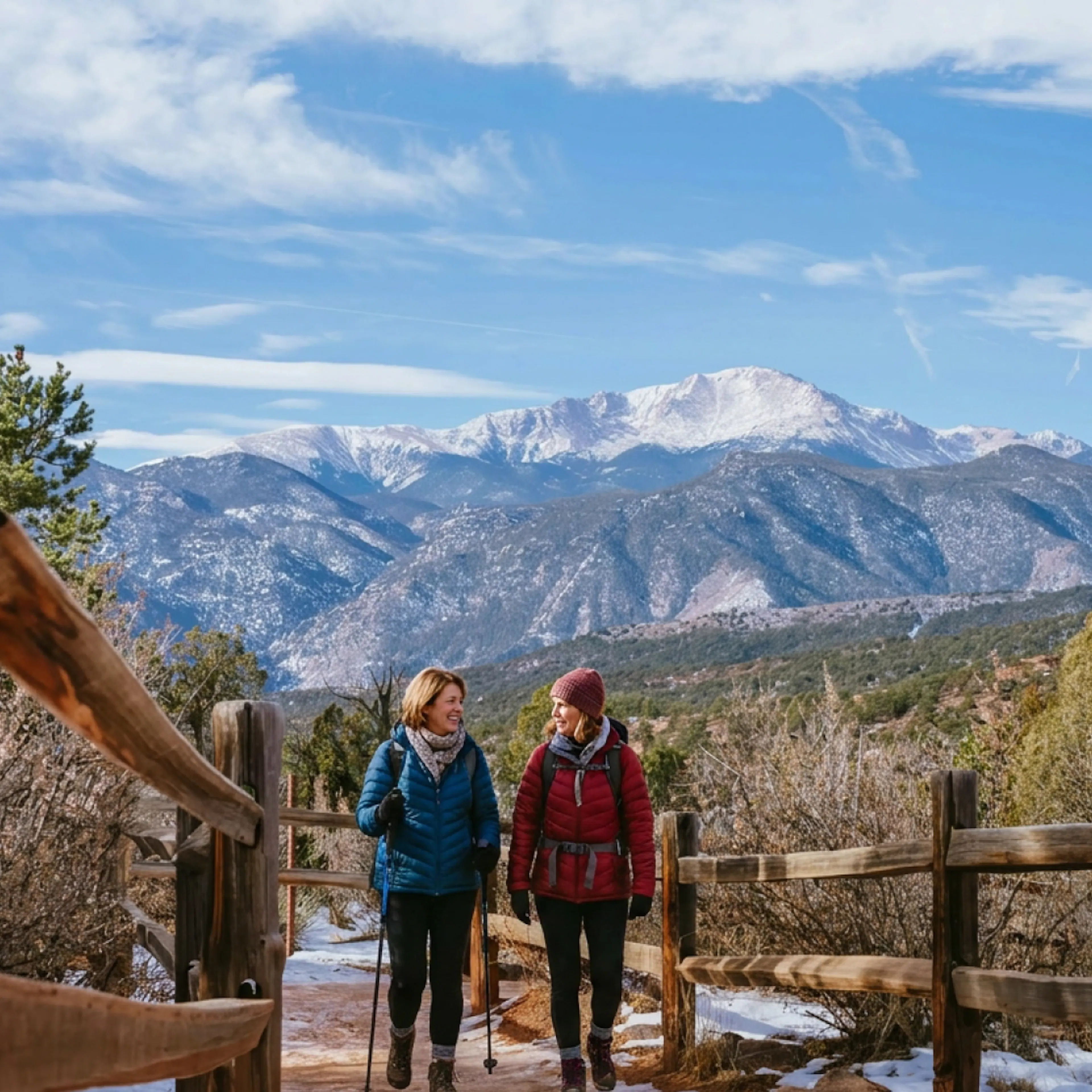 Two hikers at Garden of the Gods in winter, with Pikes Peak in the background. The hikers are women in menopause in Colorado Springs, CO.