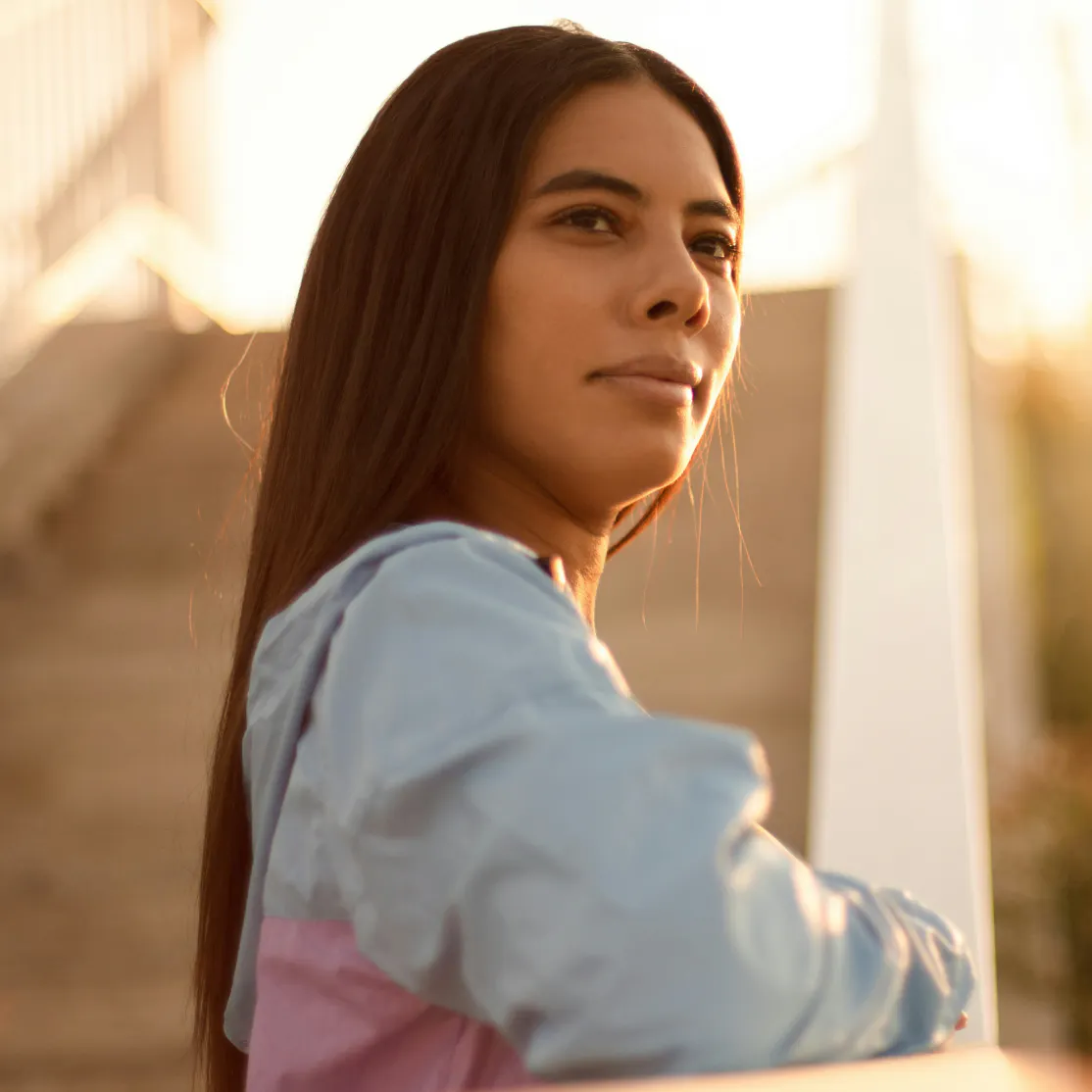 A woman in midlife looking into the distance at dusk.