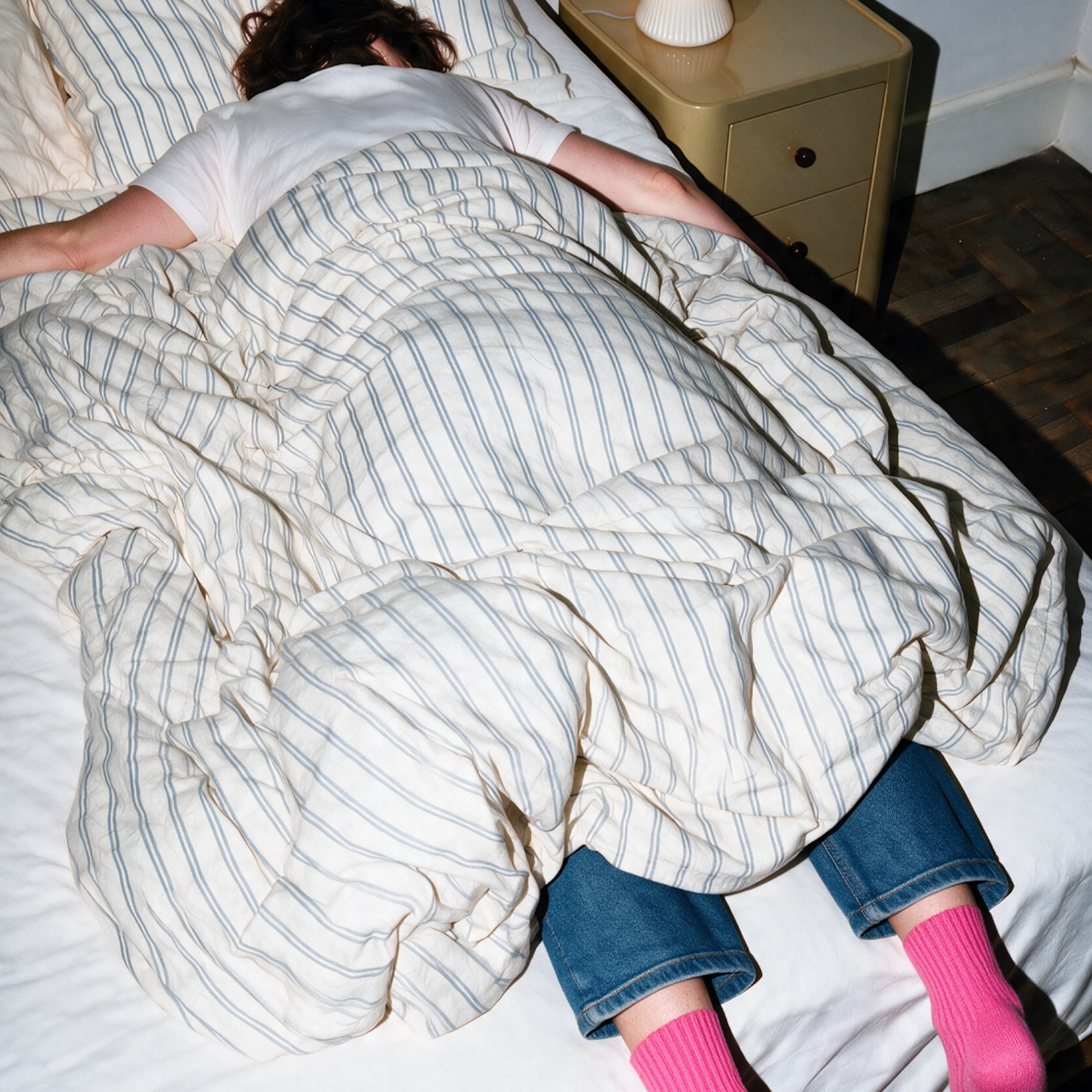 A woman dealing with sudden crashing fatigue. She's lying face-down on her belly in bed.