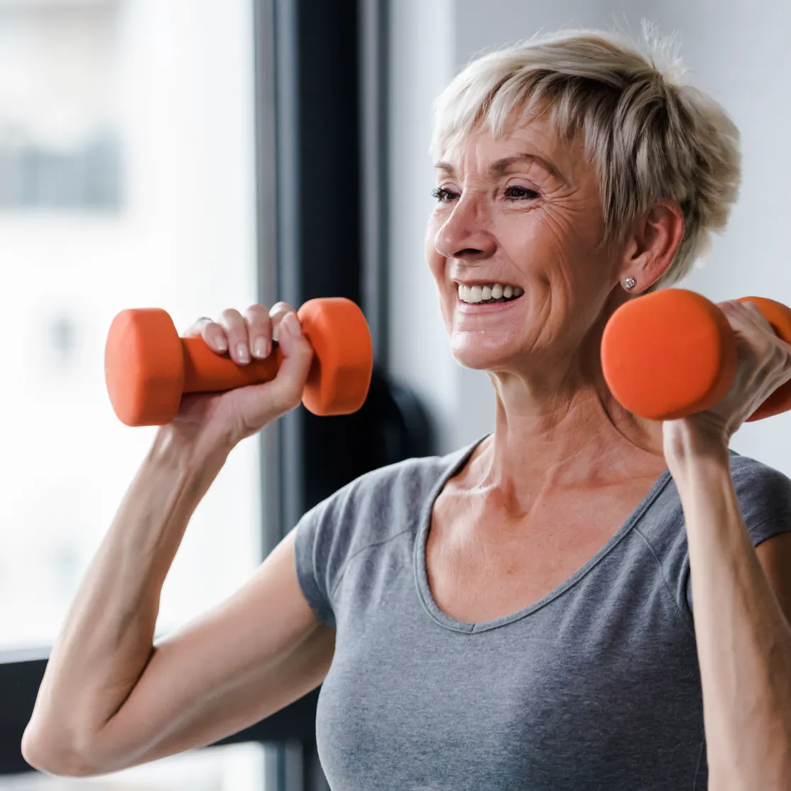 A woman in menopause lifting weights in a press move.