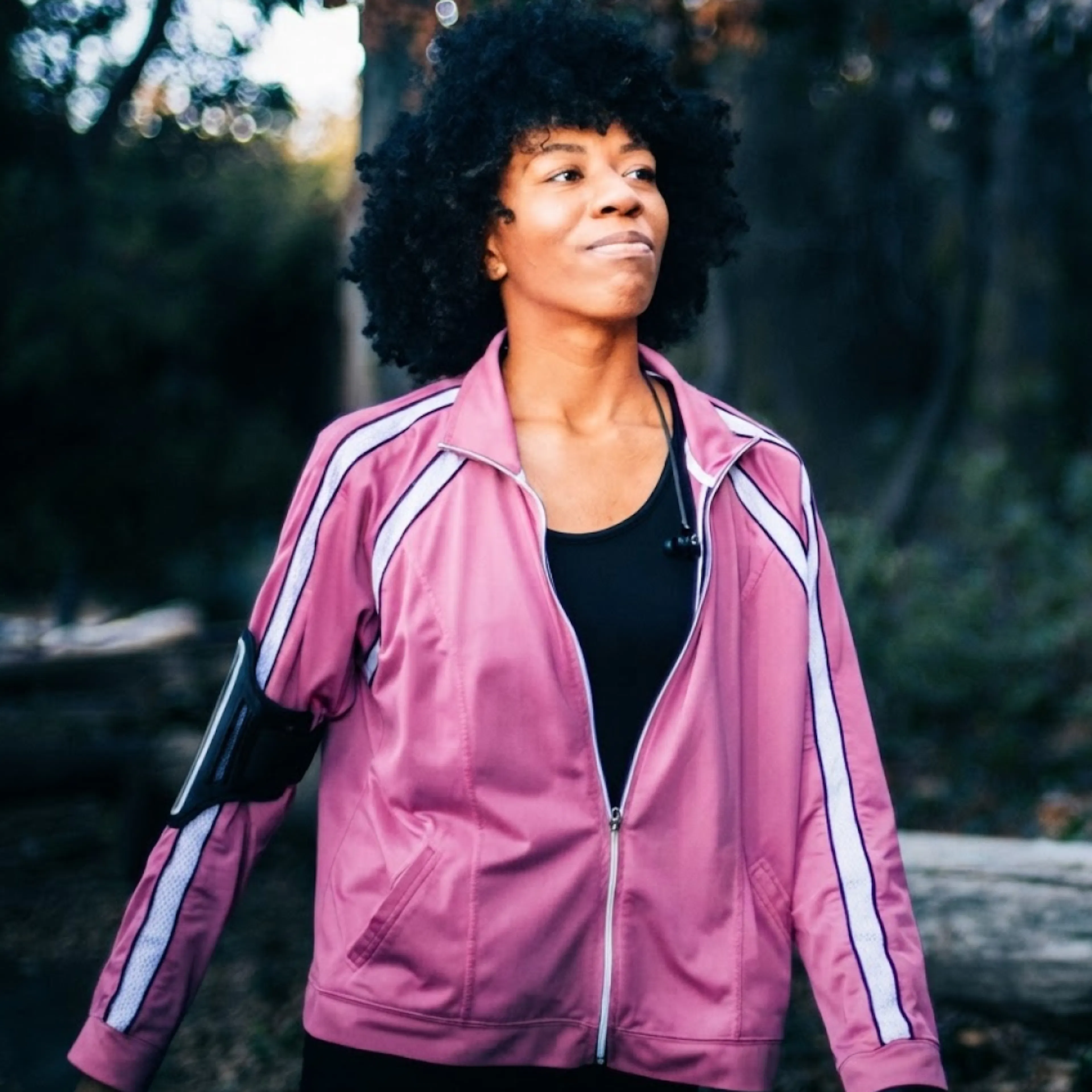 A woman in perimenopause, going for a walk outside. She's wearing a pink windbreaker.