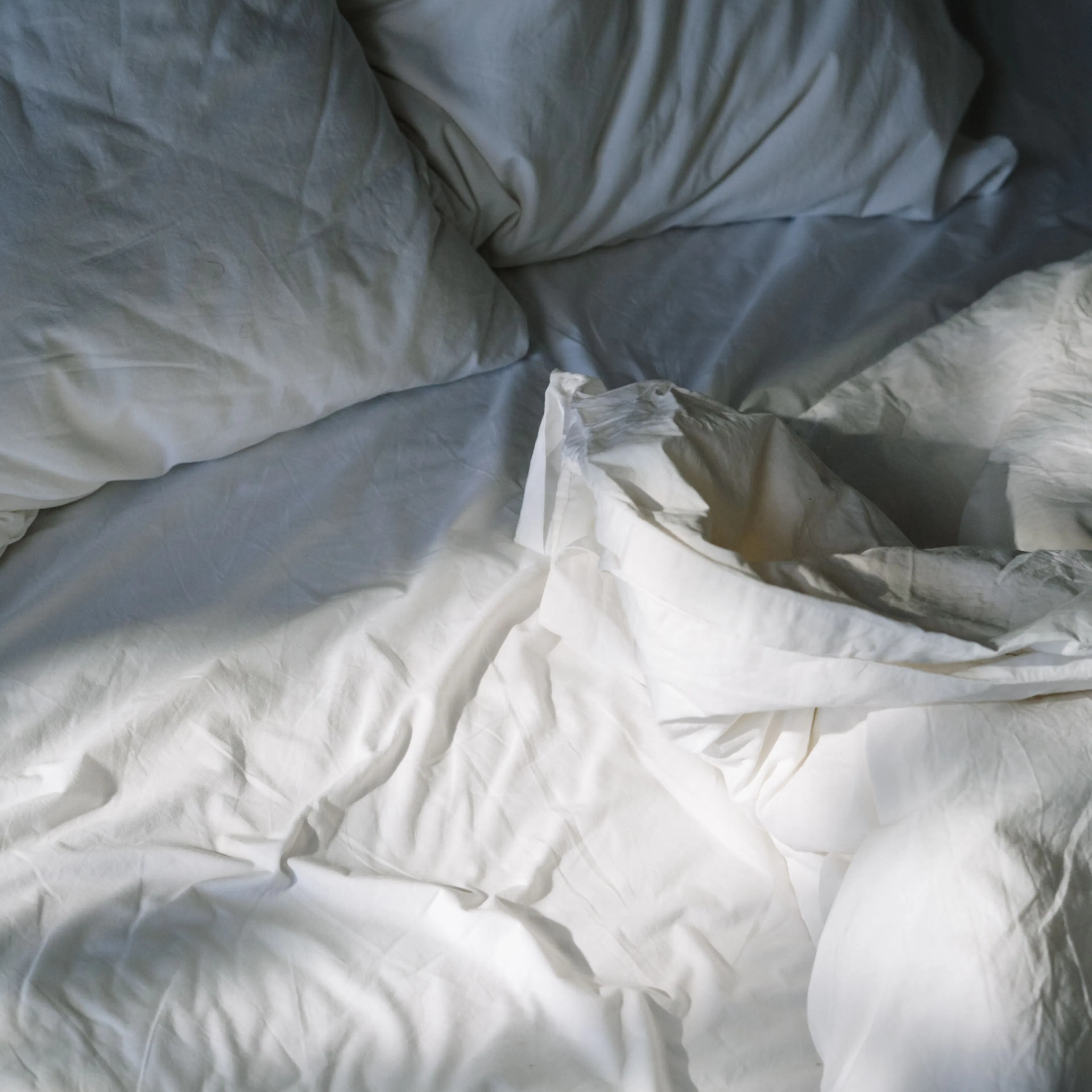 A close-up image of an unmade bed in natural light.