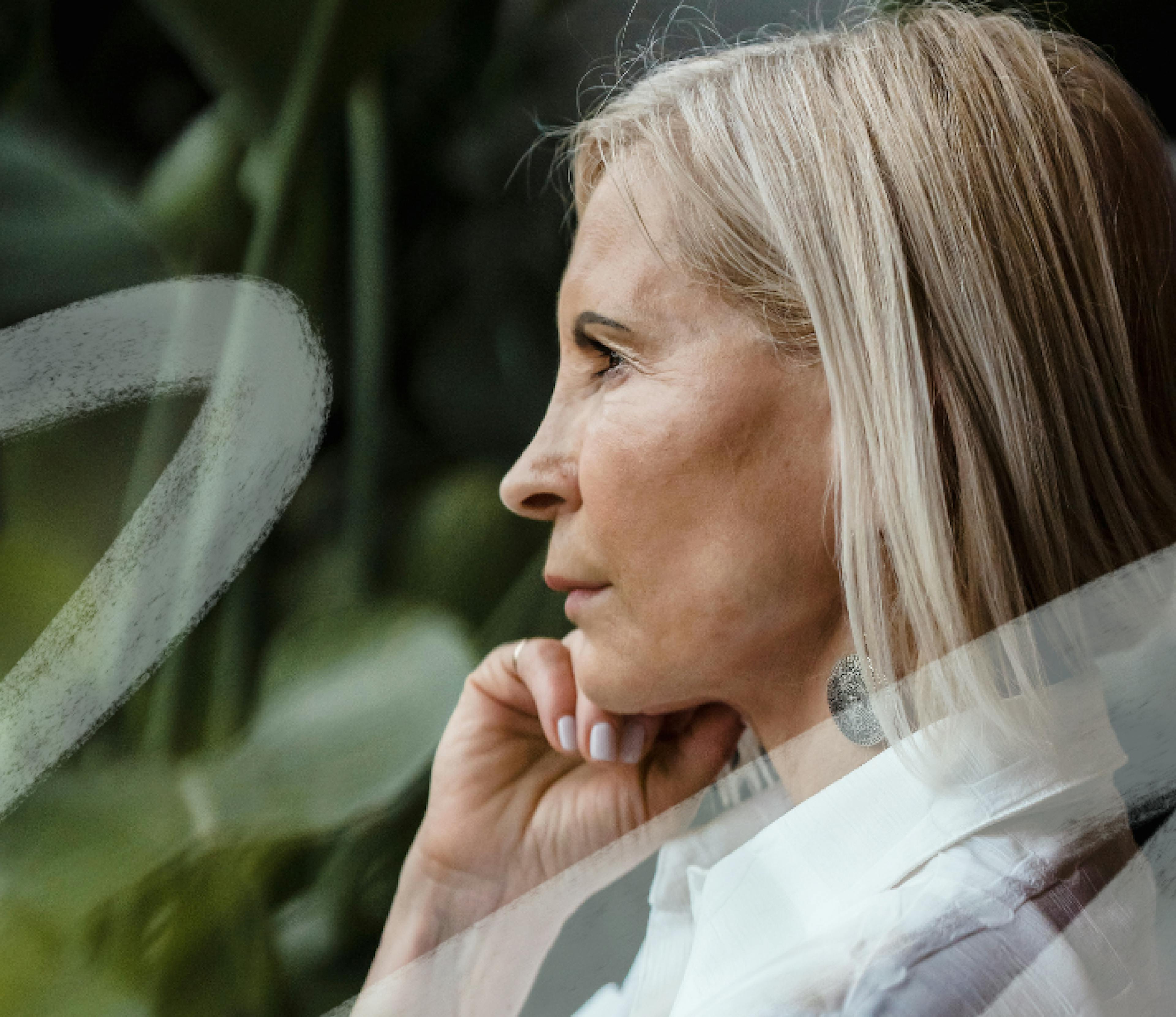 A woman looking into the distance, hand on chin