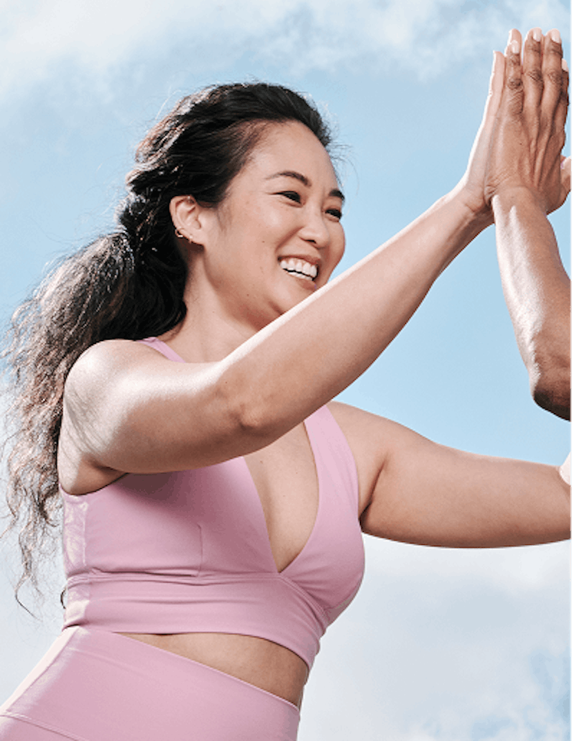 Photograph of woman smiling whilst high-fiving another woman