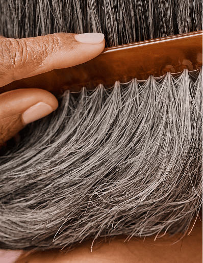 Close cropped photograph of woman combing her grey hair