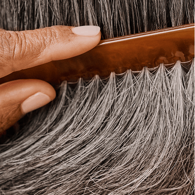 Close cropped photograph of woman combing her grey hair
