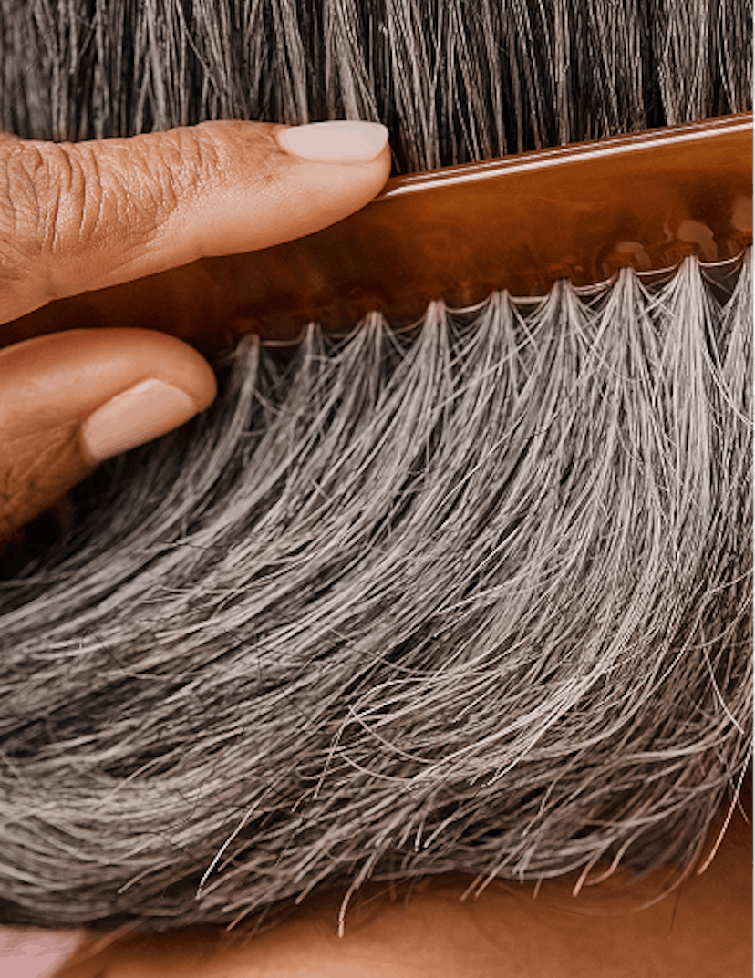 Close cropped photograph of woman combing her grey hair