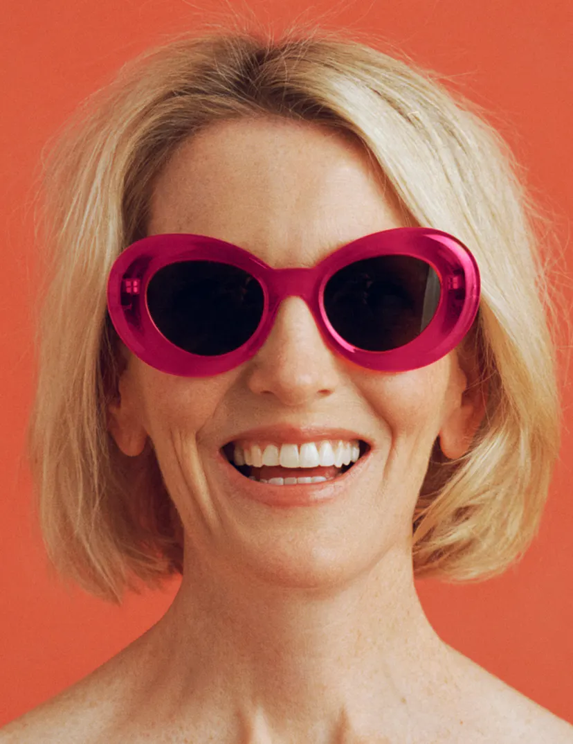 Photograph of woman wearing bright pink sunglasses and smiling